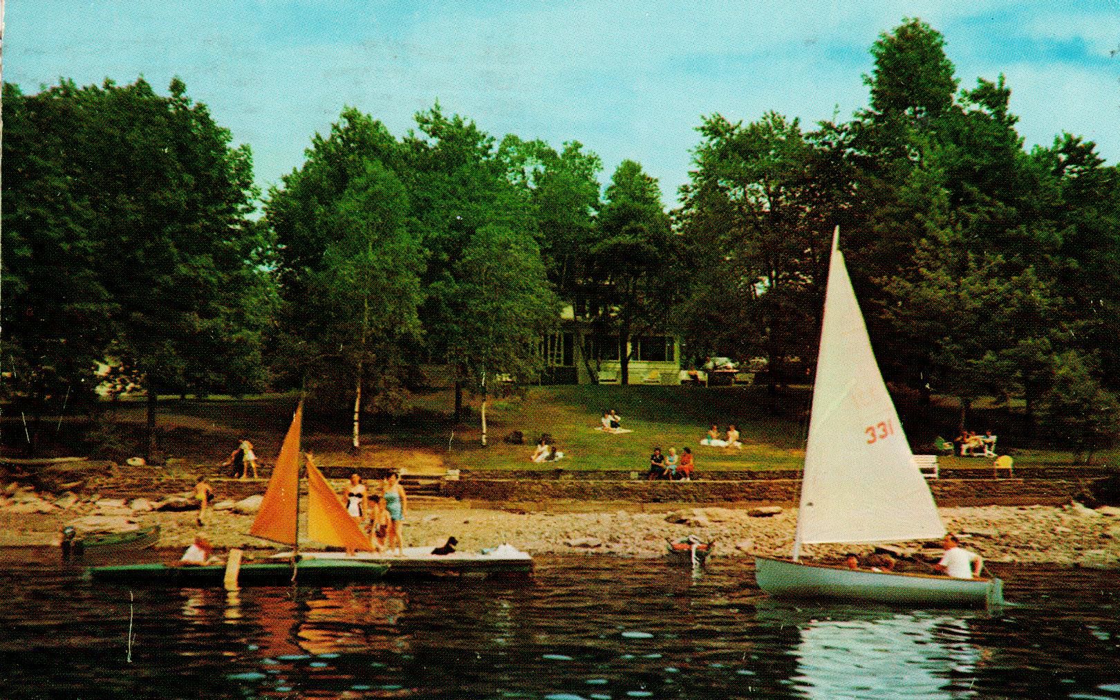 a group of people on a lake with boats and trees