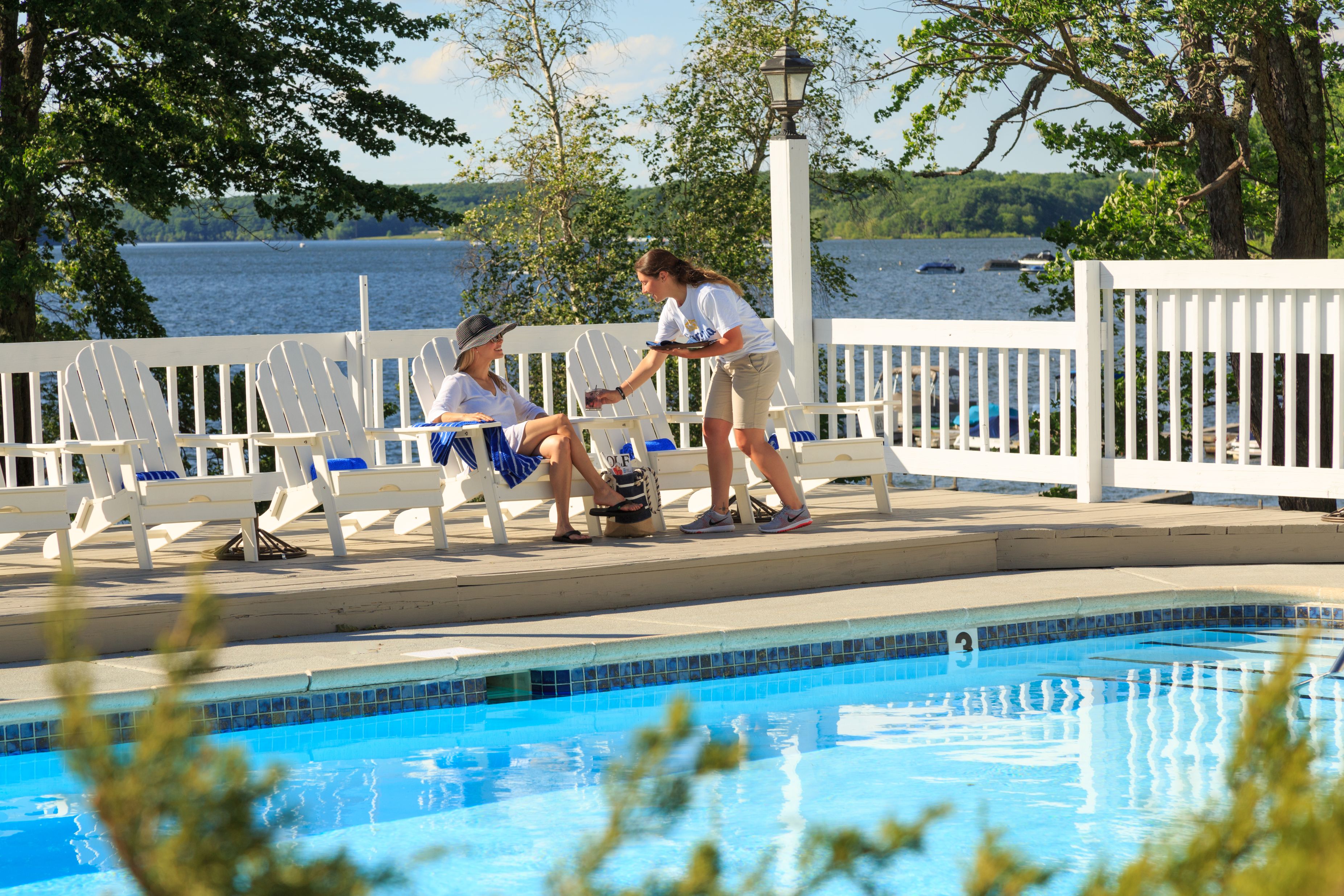 a woman and a woman sitting on a bench by a pool