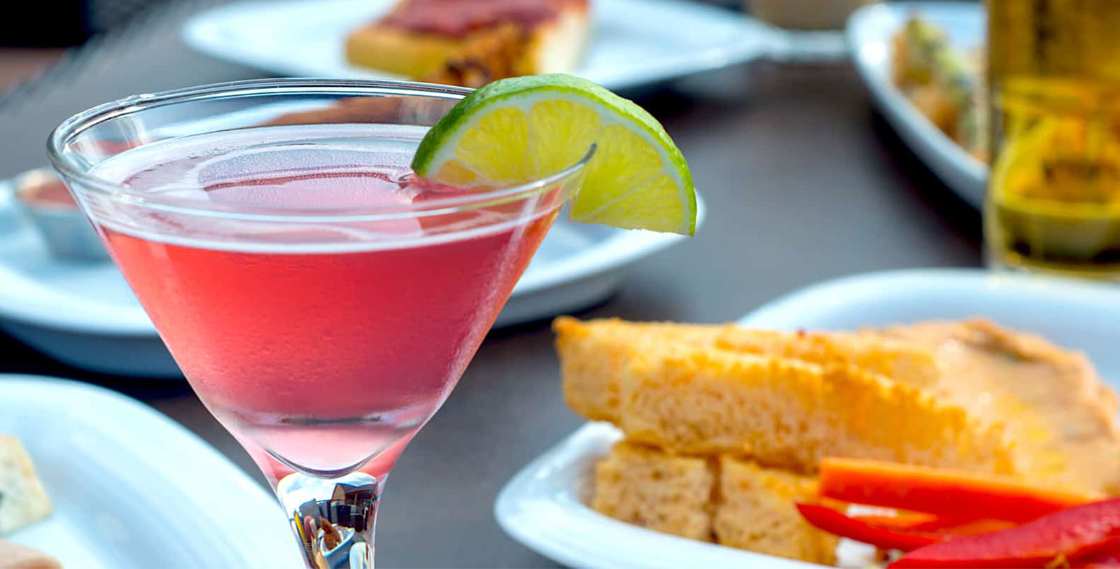 a glass of pink liquid with a lime wedge on top of it