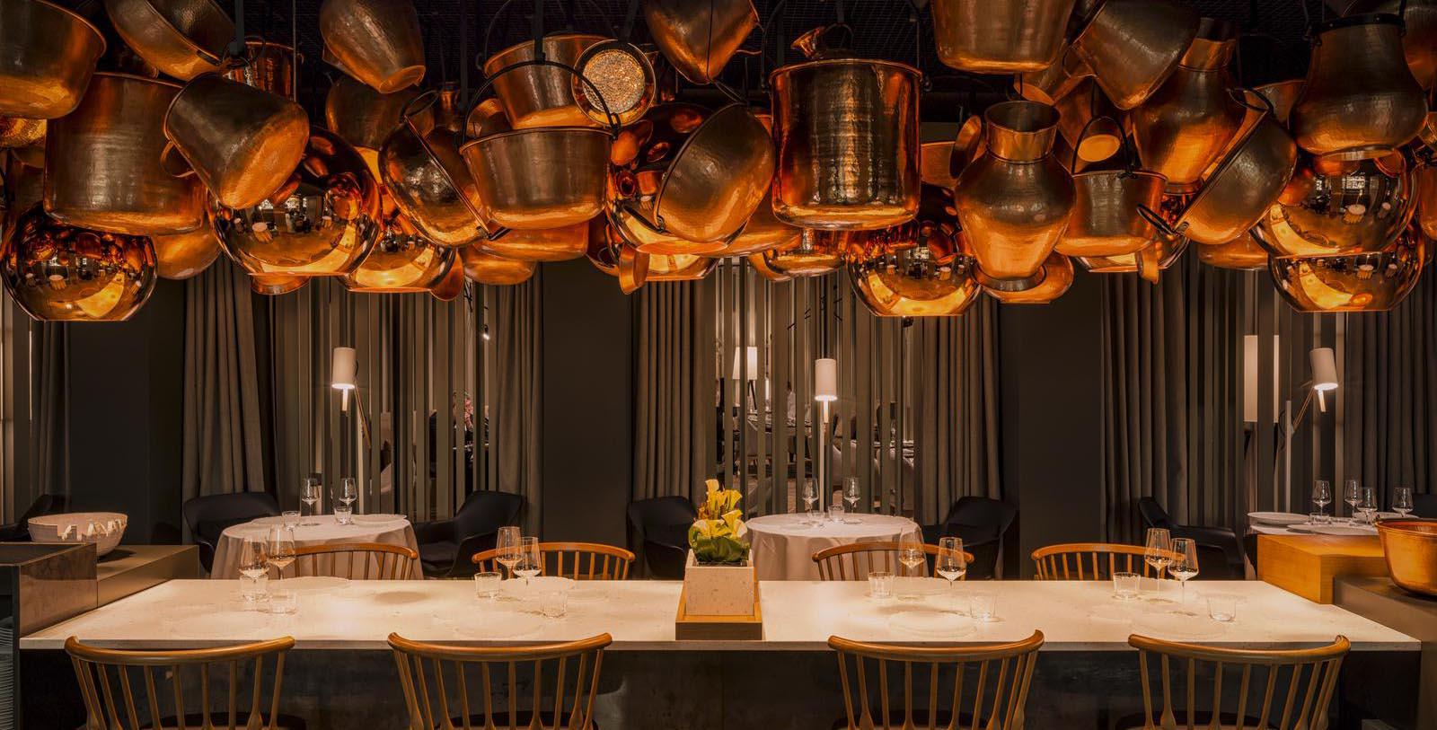 a room with a table and chairs and pots from the ceiling