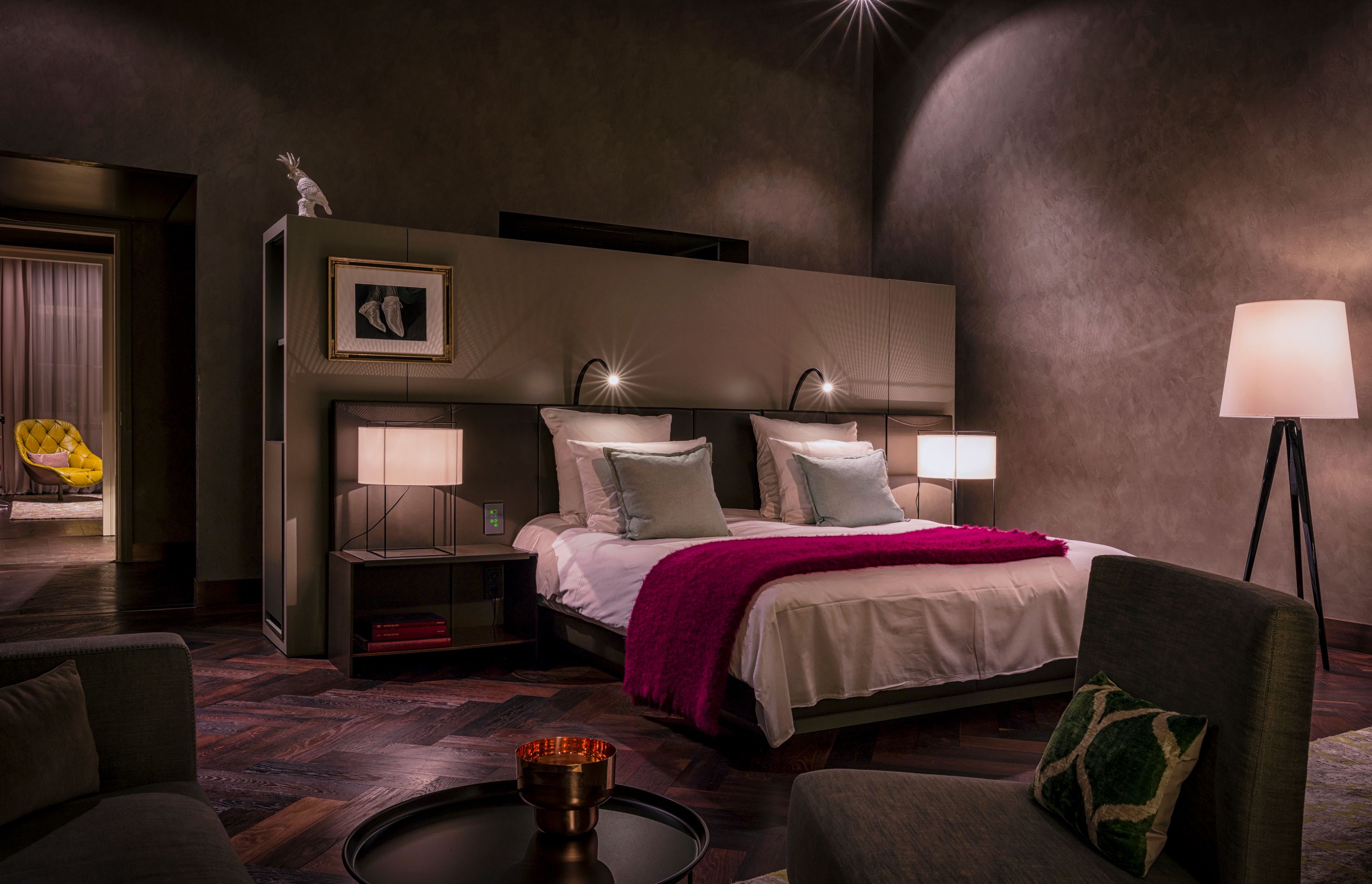 a bed with a pink blanket and a lamp in a dark room