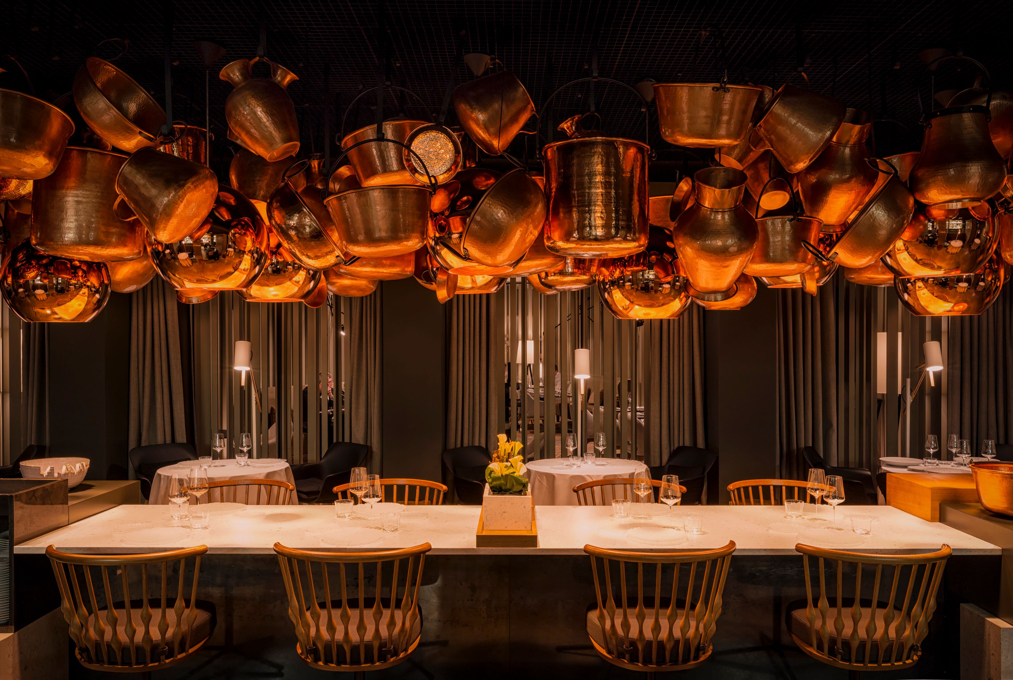 a room with a table and chairs and pots from the ceiling