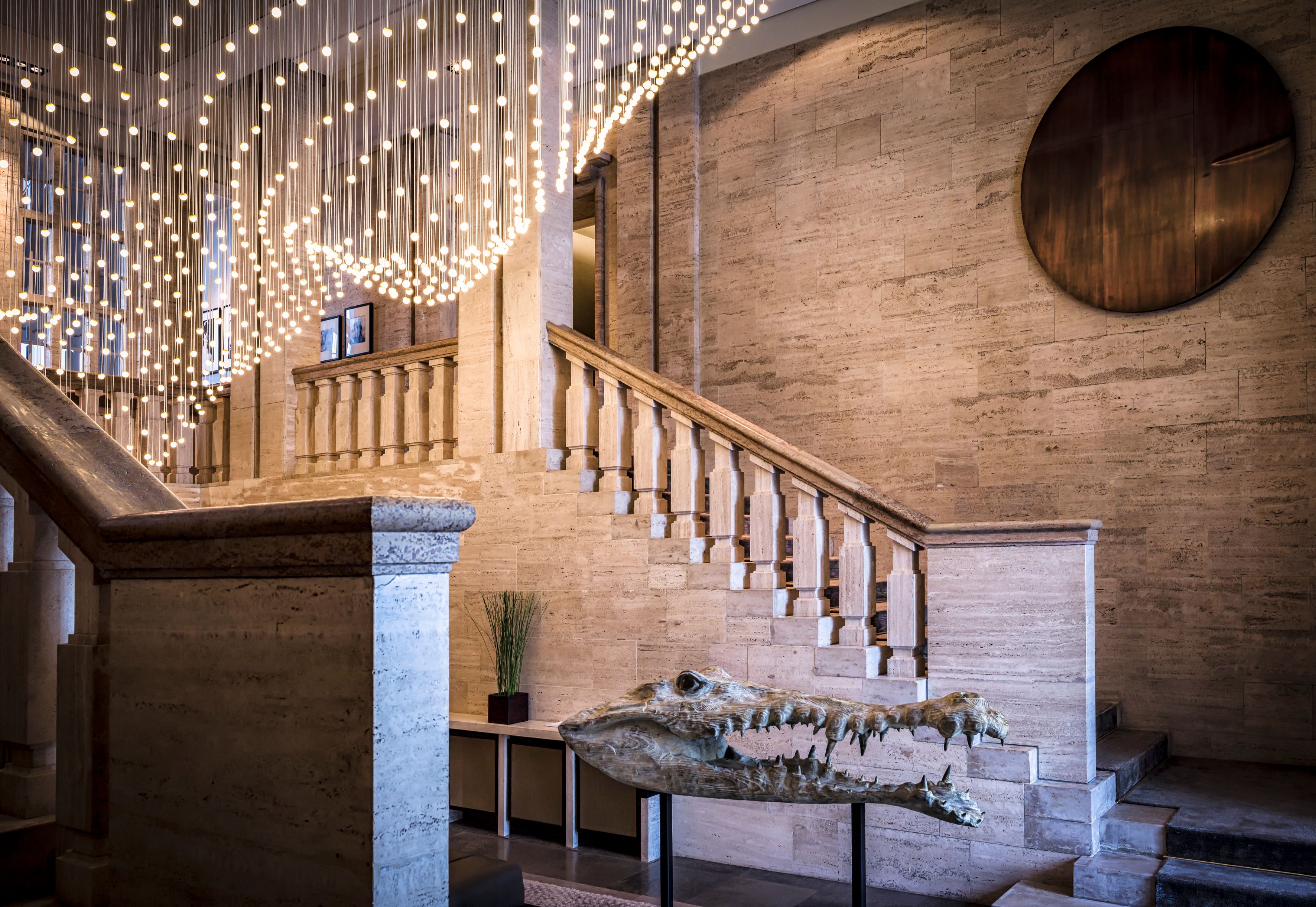 a large stone staircase with a large chandelier from it