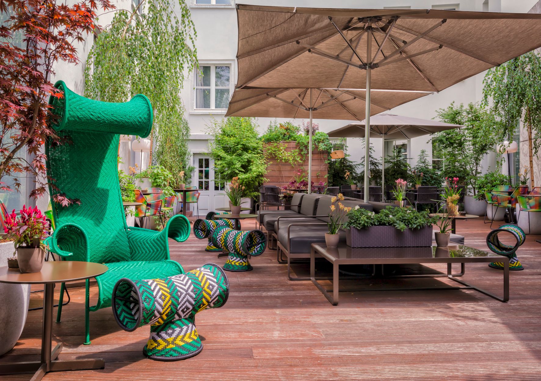 a patio with a green chair and chairs and a table and umbrella