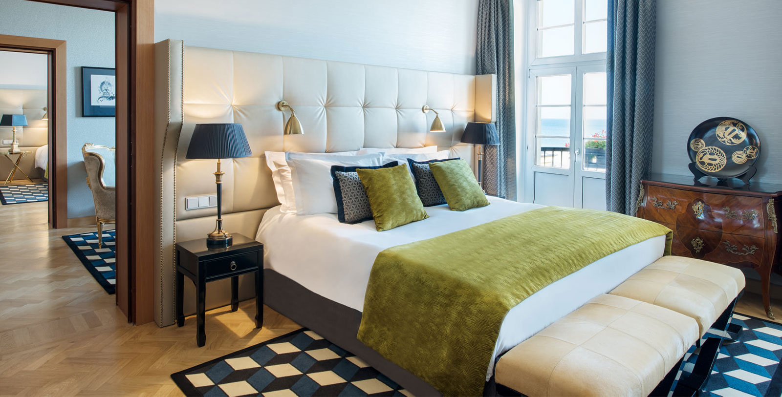 a bed with green pillows and a black lamp