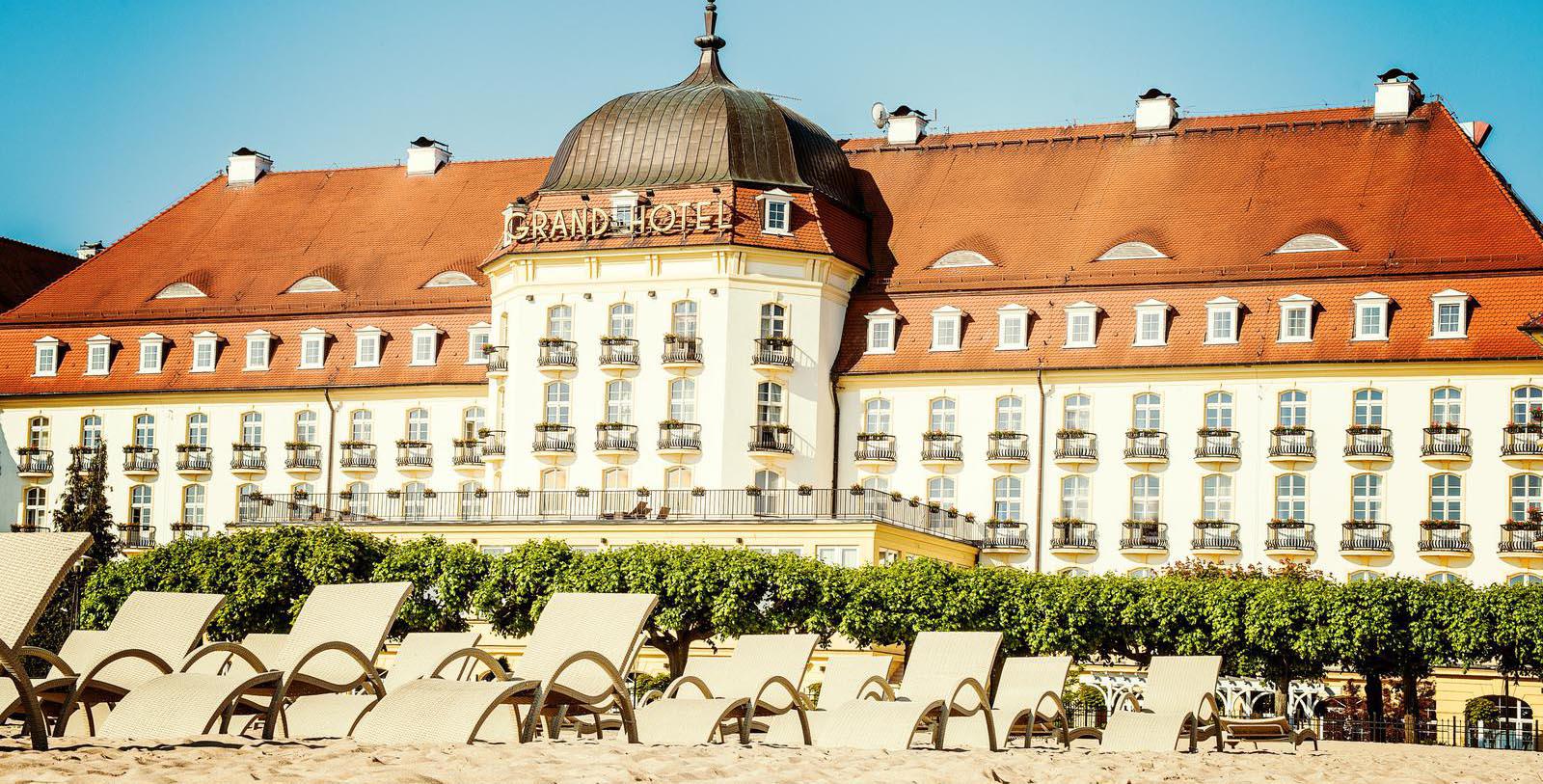 a large white building with a beach and chairs
