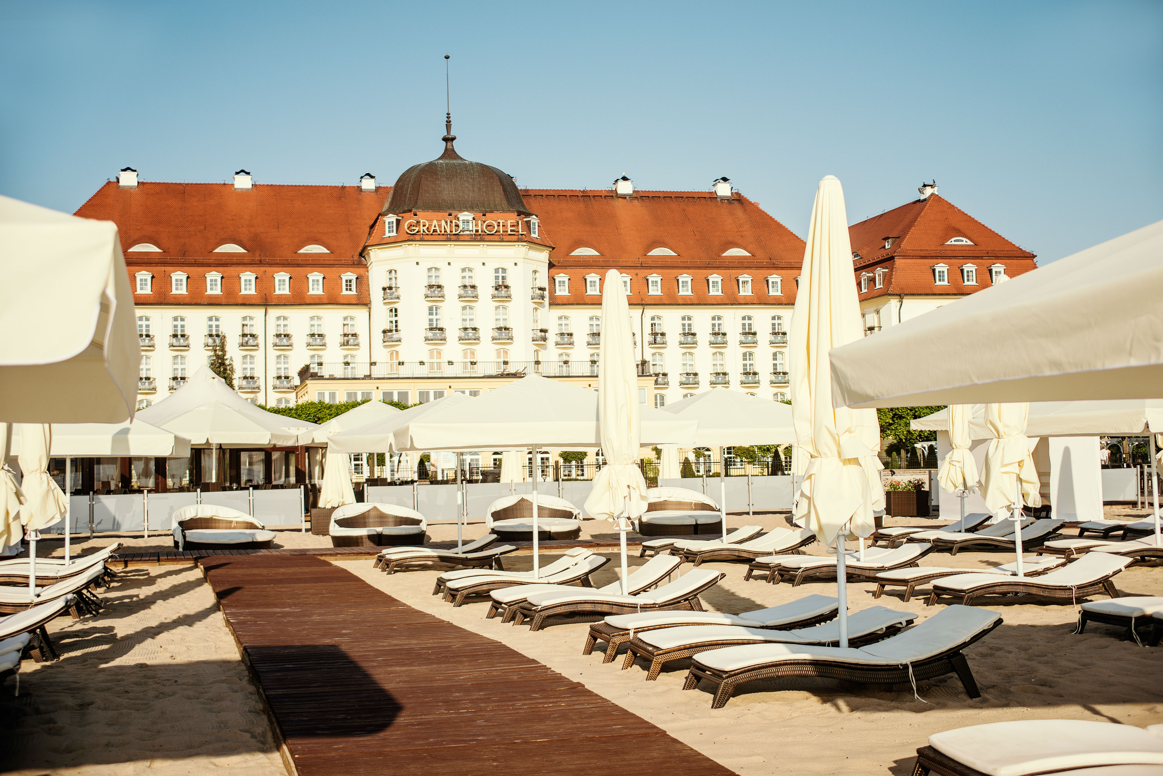 a group of lounge chairs and umbrellas in front of a large building