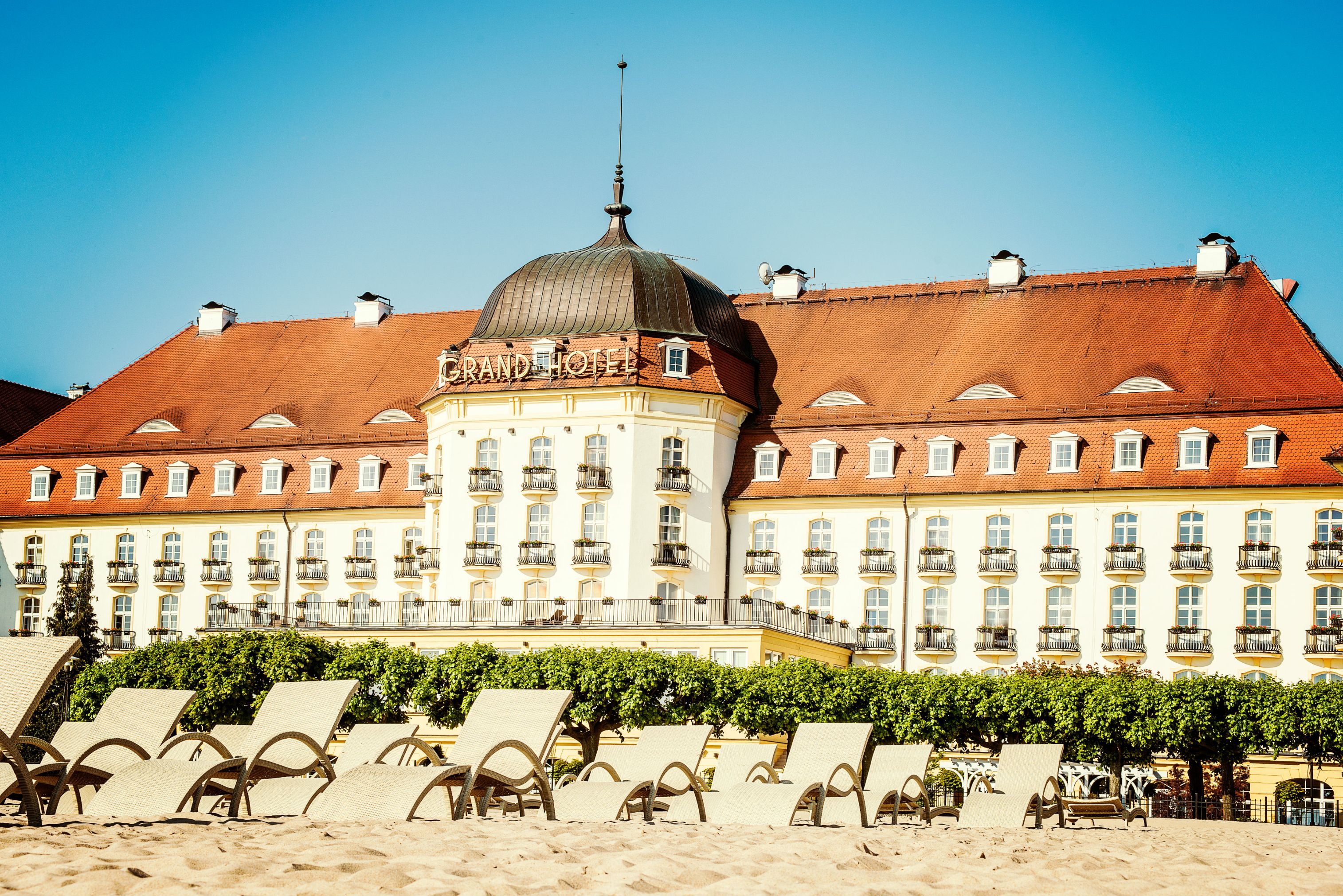 a large building with lounge chairs on the beach