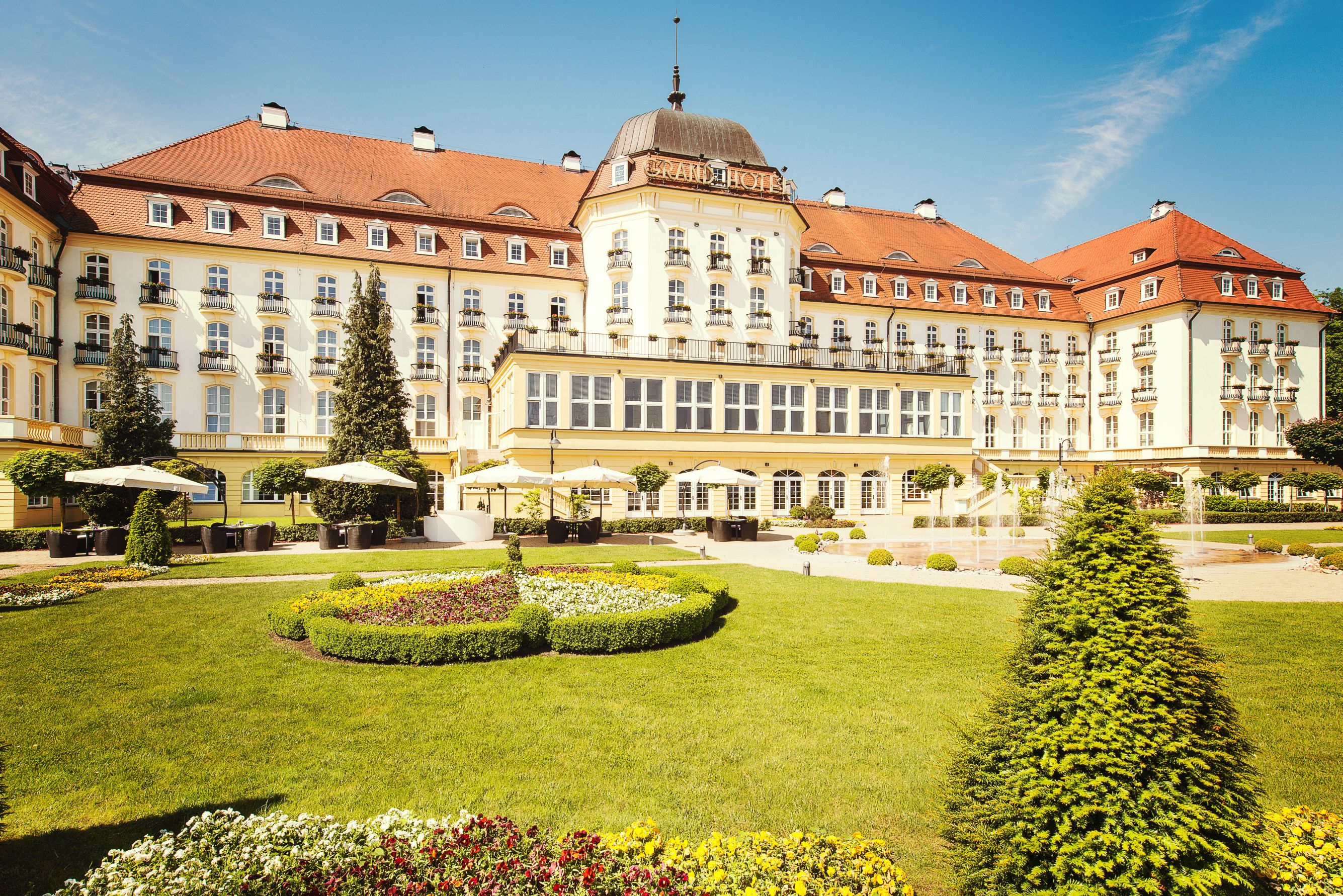 a large building with a lawn and bushes with Nymphenburg Palace in the background