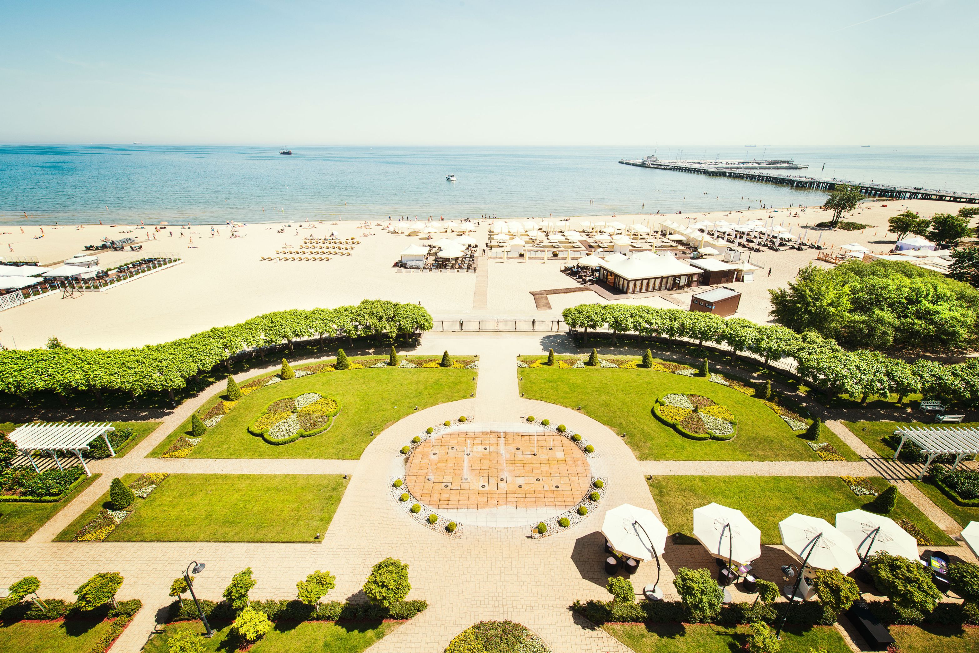 a large beach with a fountain and a body of water