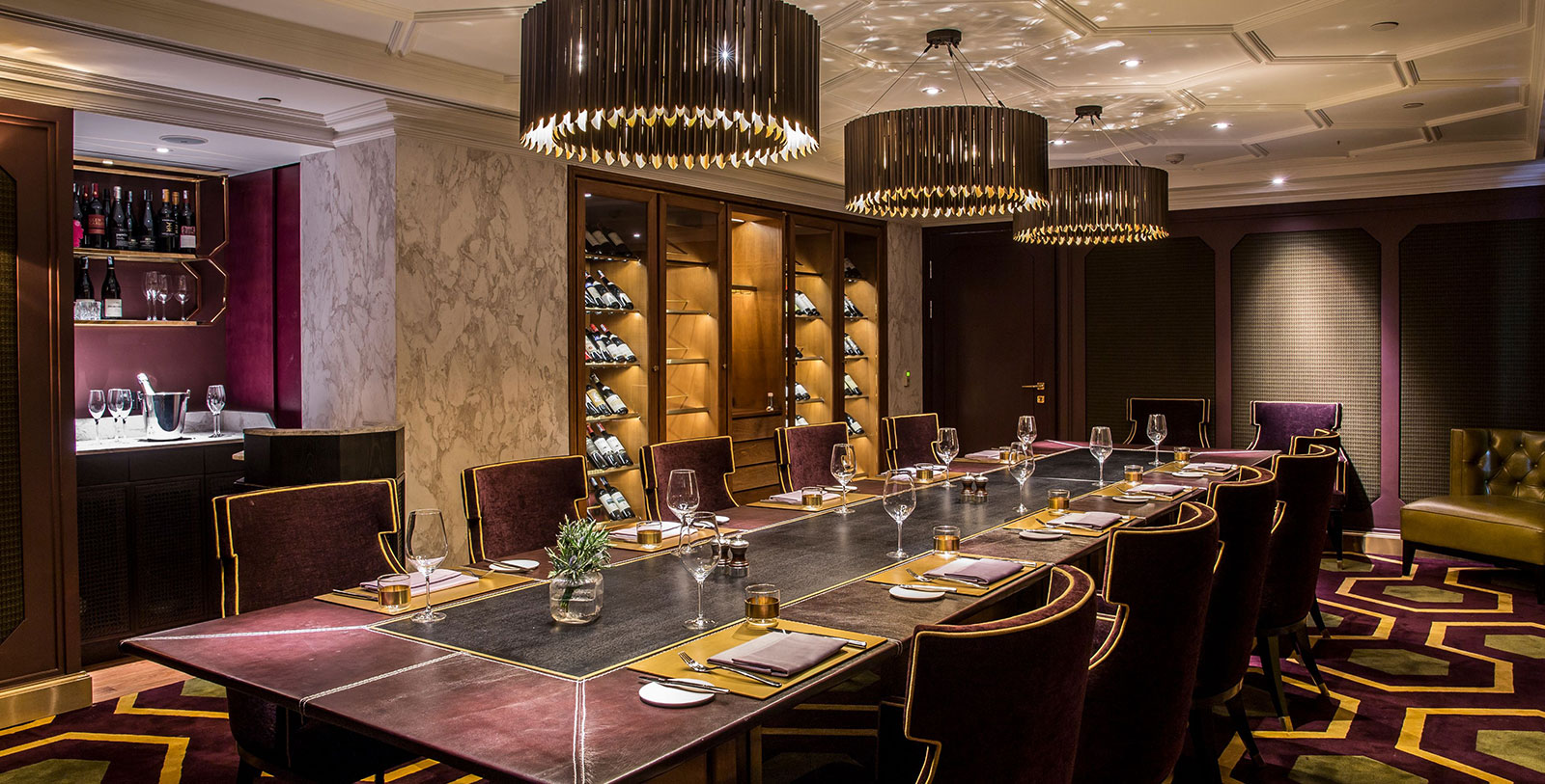 a large table with wine glasses and chairs in a room with a wine rack