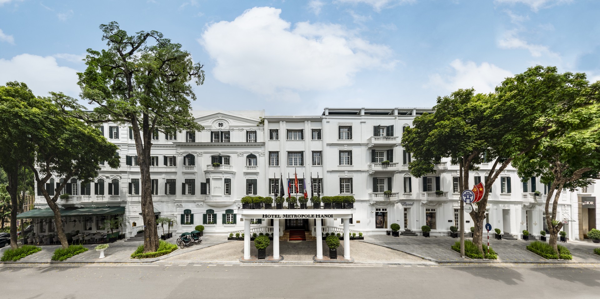 a white building with trees and flags