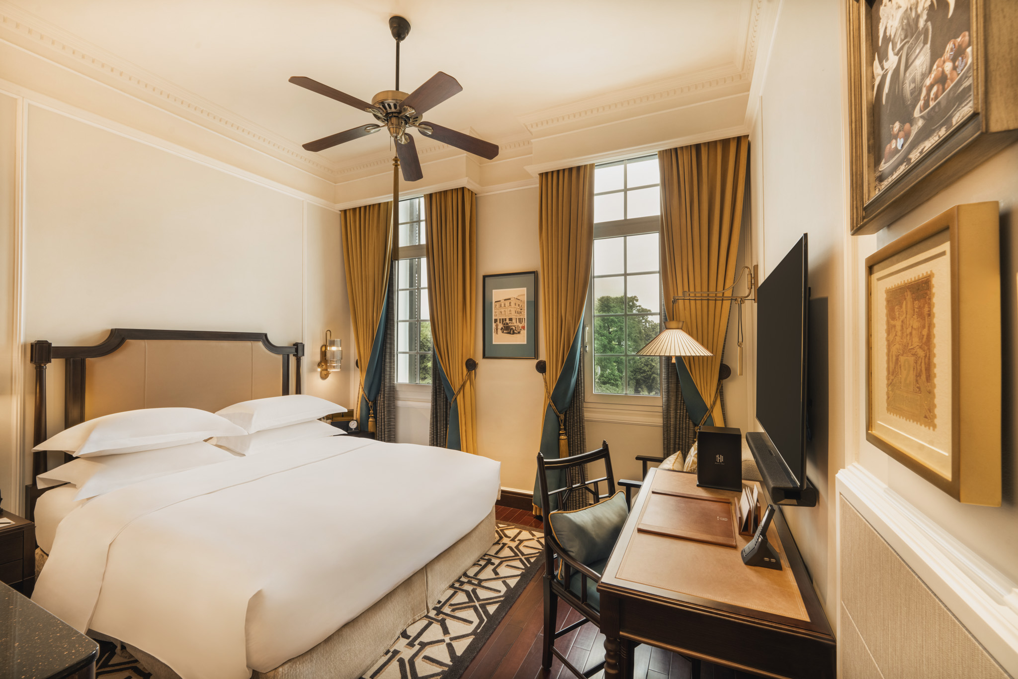 a room with a bed and a desk and a fan