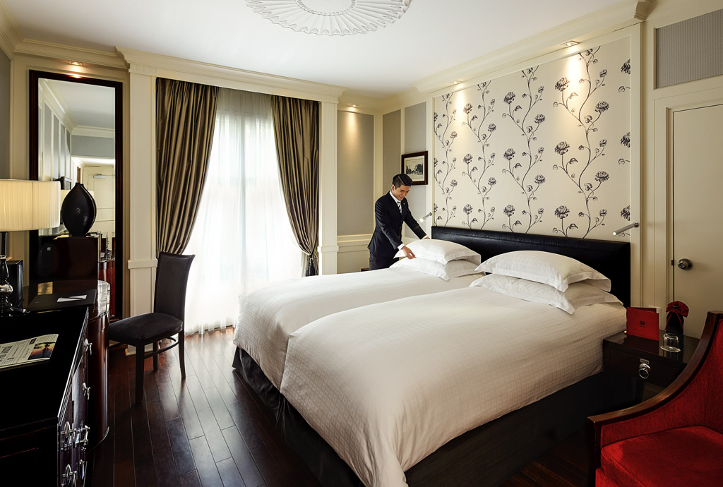 a man in a suit making a bed in a hotel room