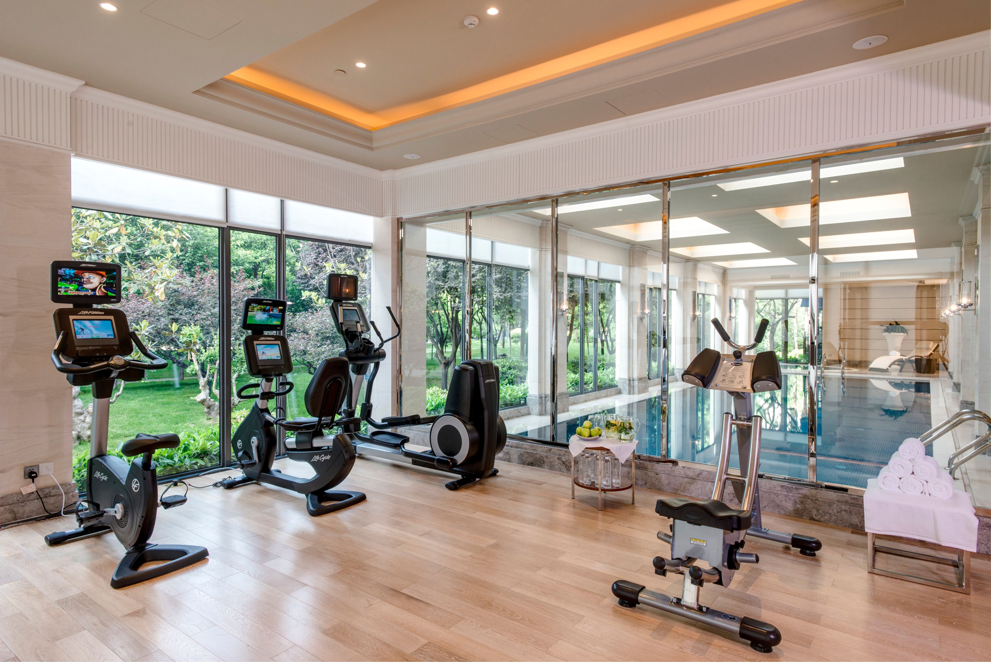 a room with exercise equipment and a pool in the background