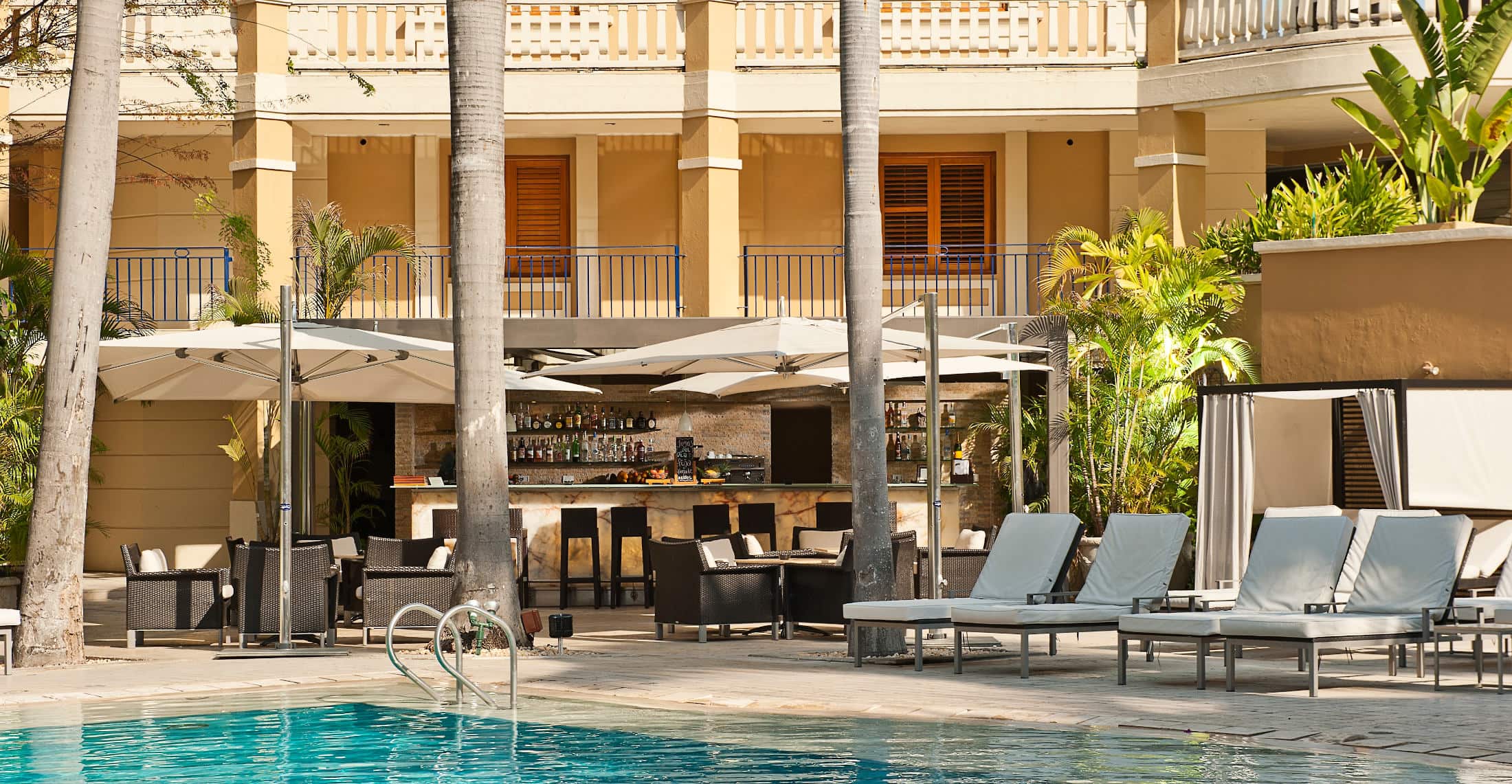 a pool with lounge chairs and a bar in the background