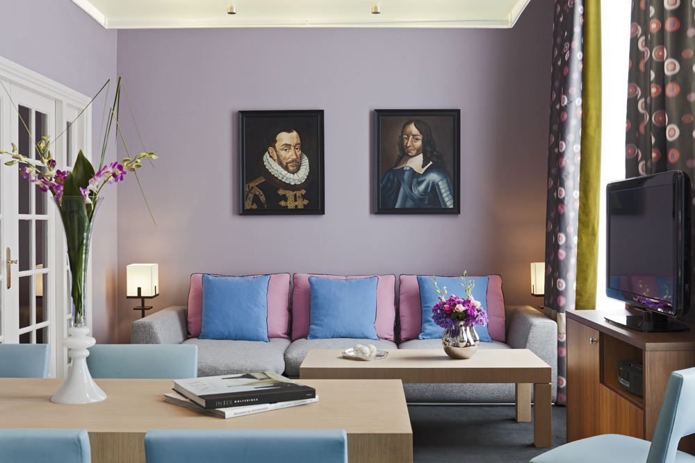 a room with a couch and a table with paintings on the wall