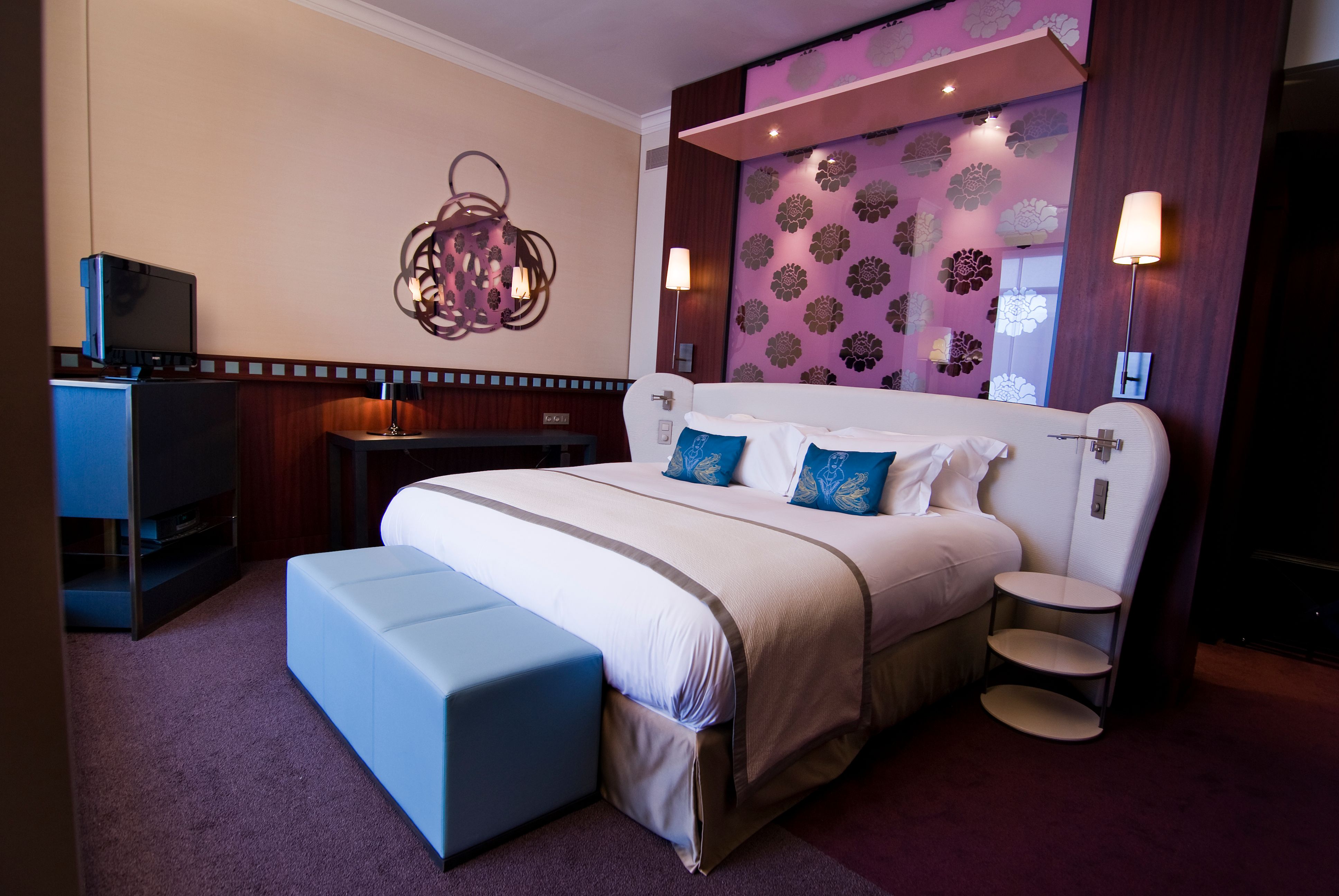 a bed with pillows and a stool in a room