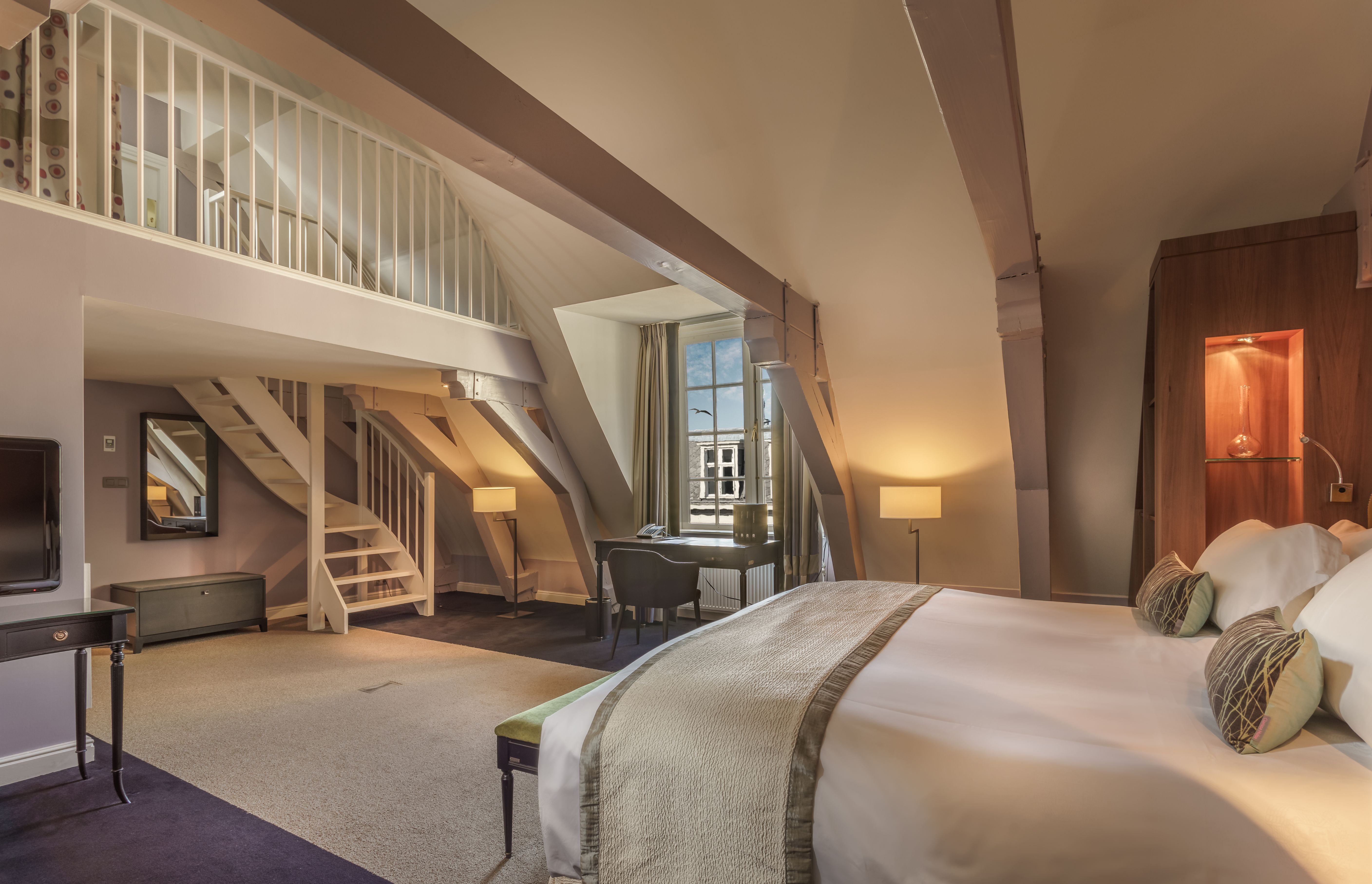 a bedroom with a desk and stairs