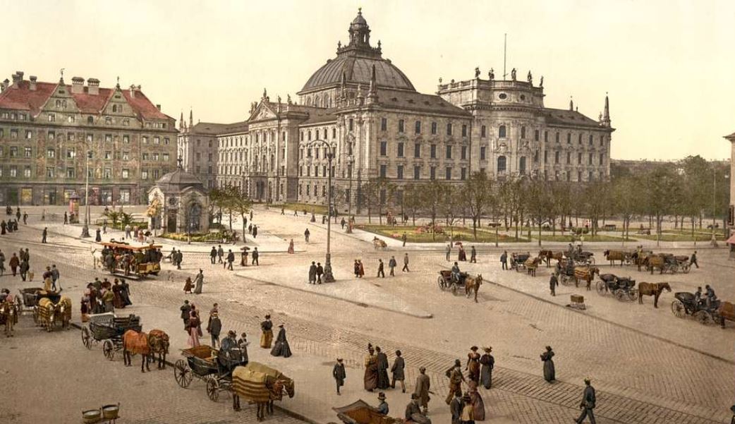 a large building with many people and carriages