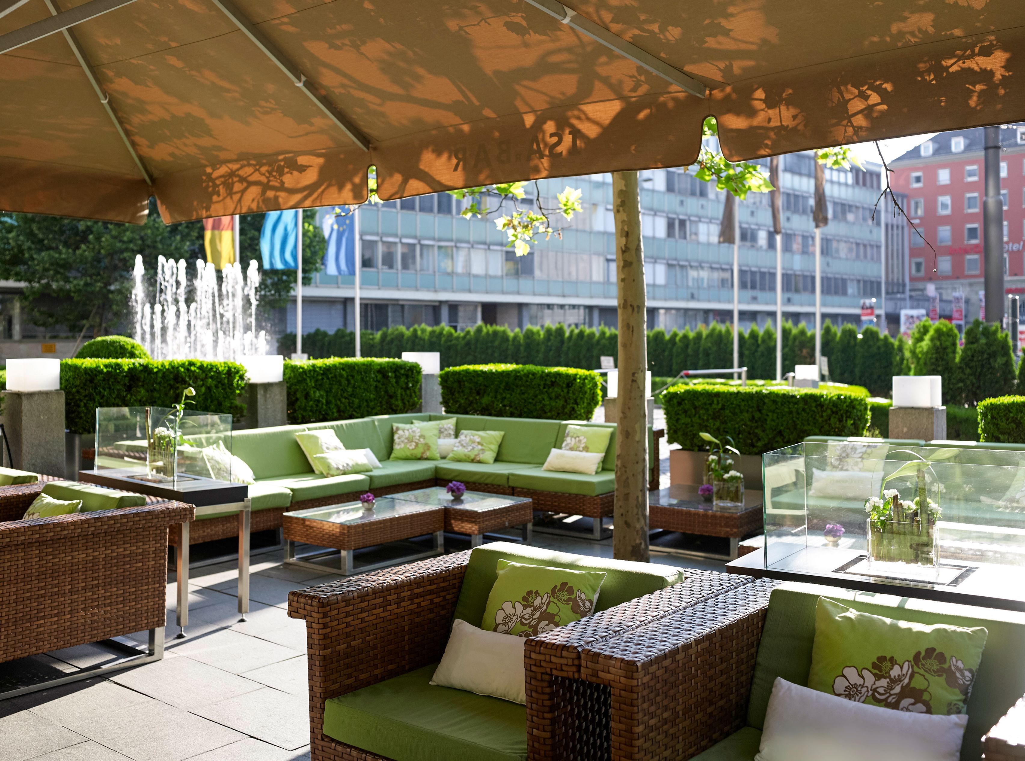 a patio area with green furniture and a fountain