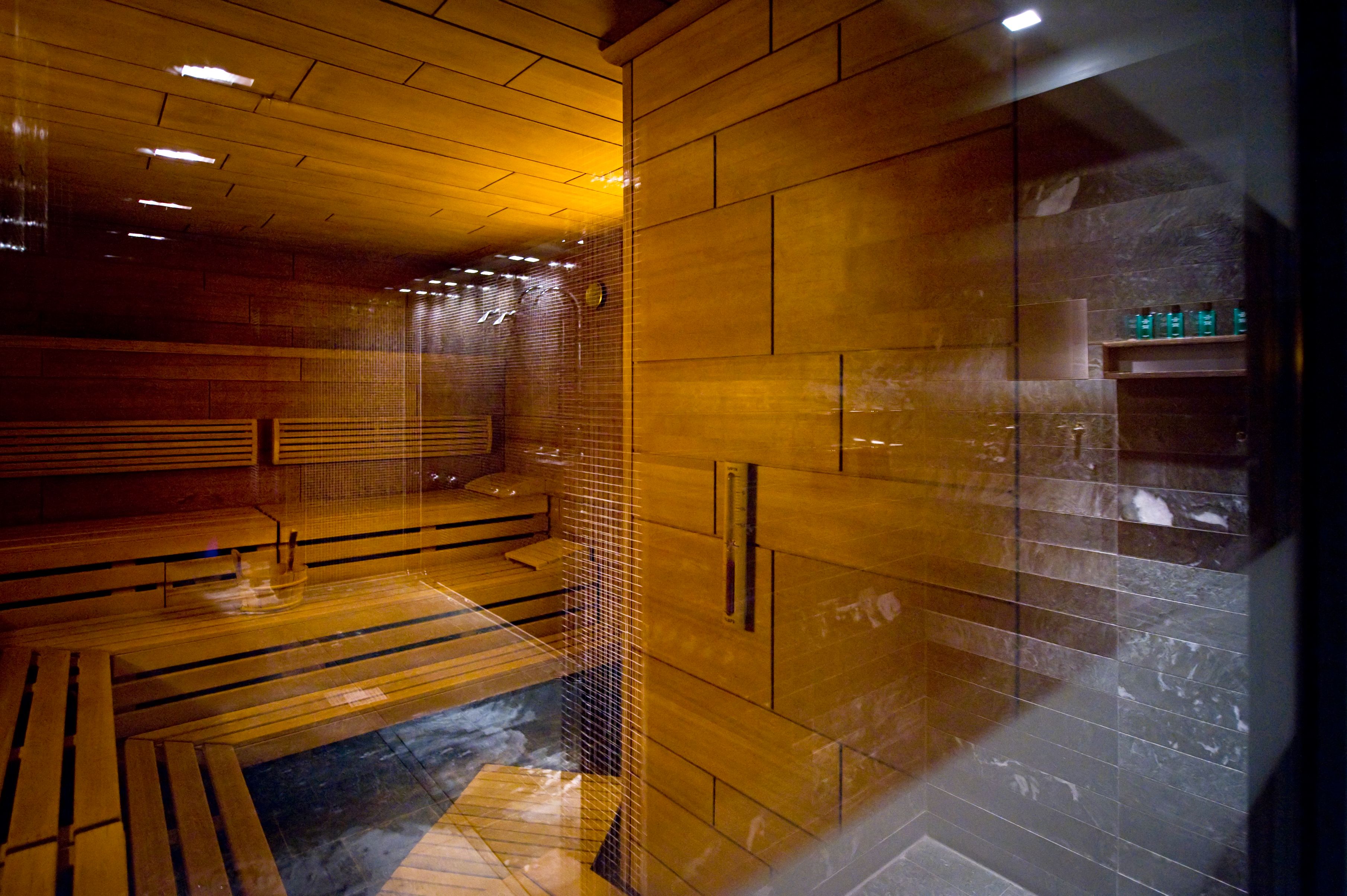 a sauna room with wood walls and a glass door