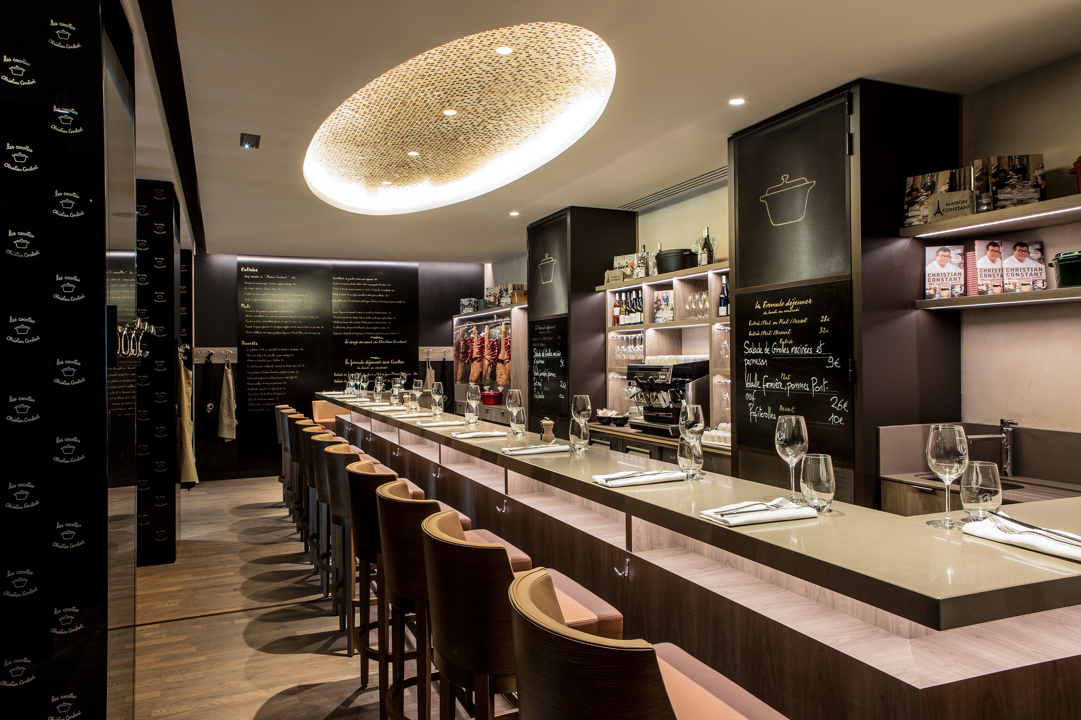 a long bar with chairs and a large light fixture