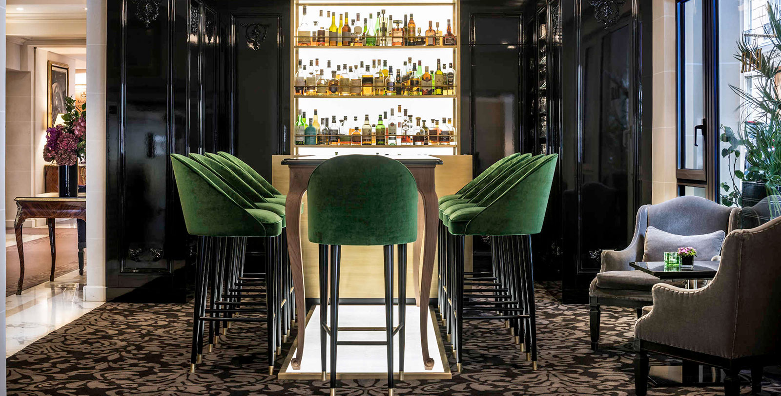 a bar with green chairs and a shelf with liquor bottles