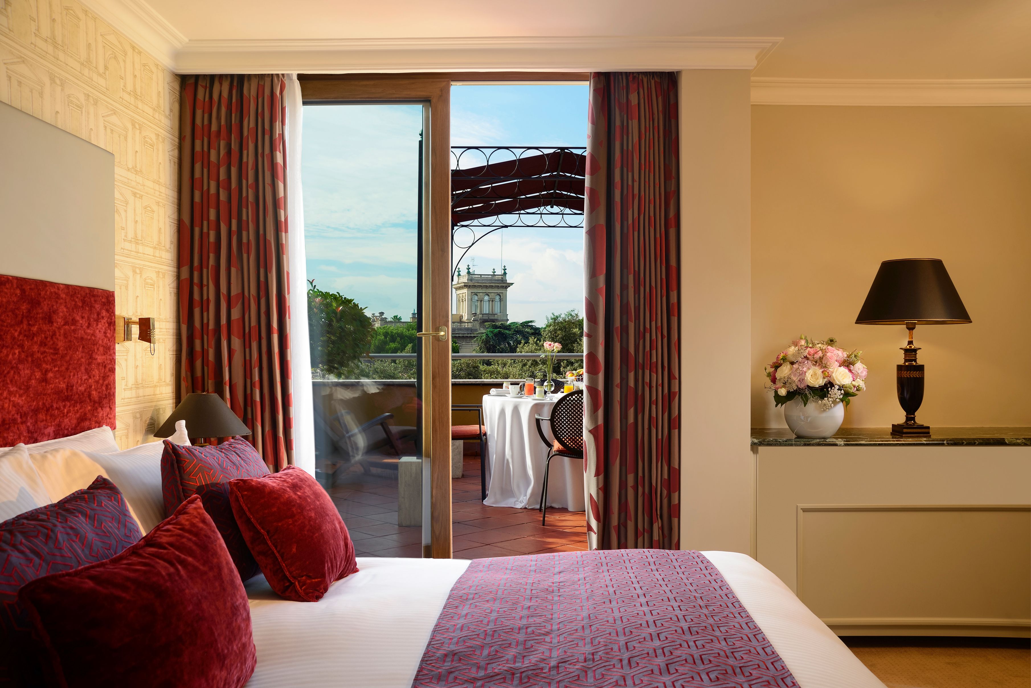 a bed with red pillows and a glass door