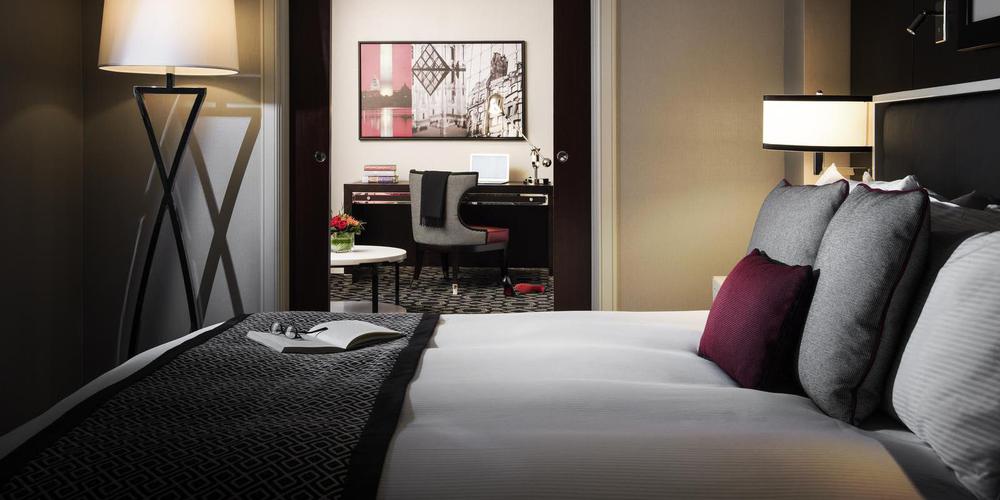 a bed with a red pillow and a desk in a hotel room