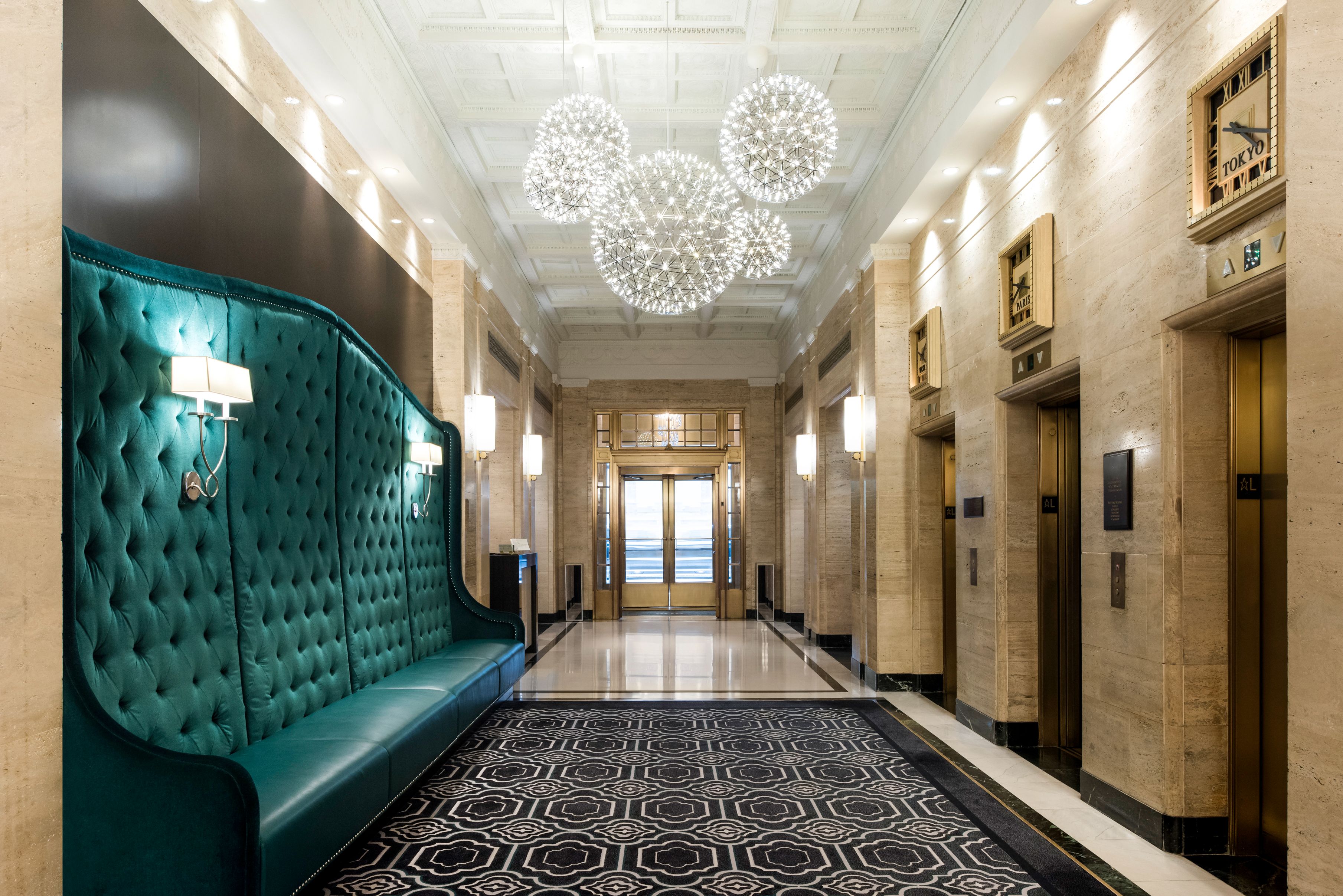 a hallway with a green couch and chandeliers