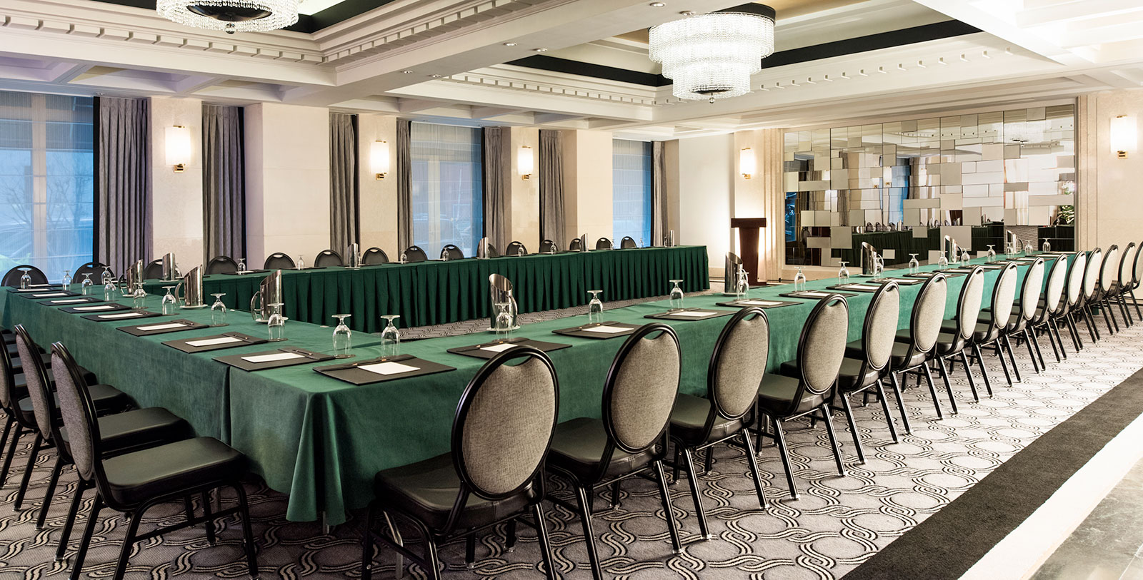 a long conference room with green tablecloths and chairs