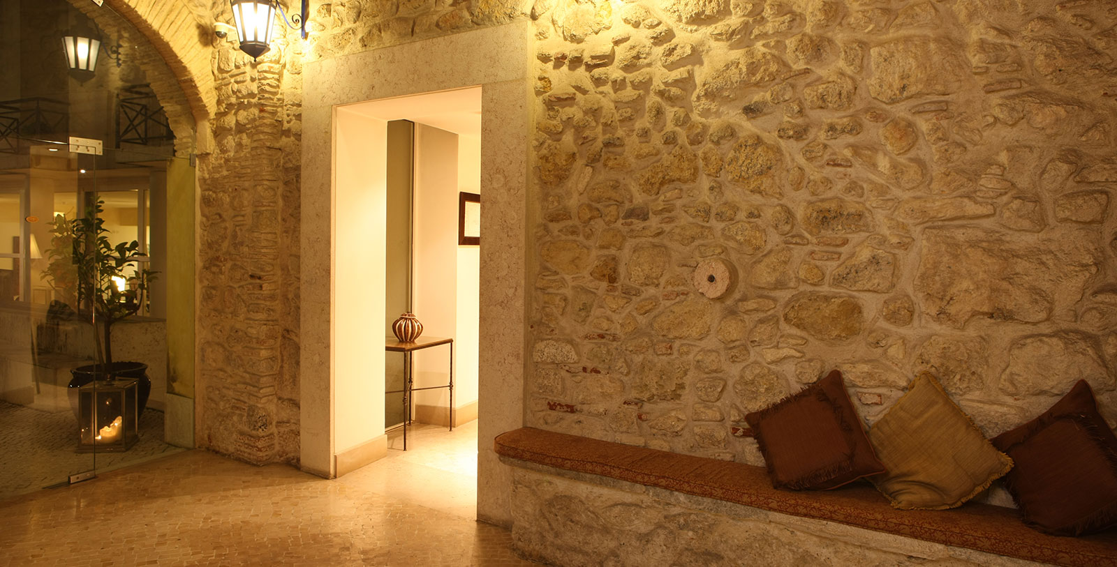 a stone wall with a bench and a lamp