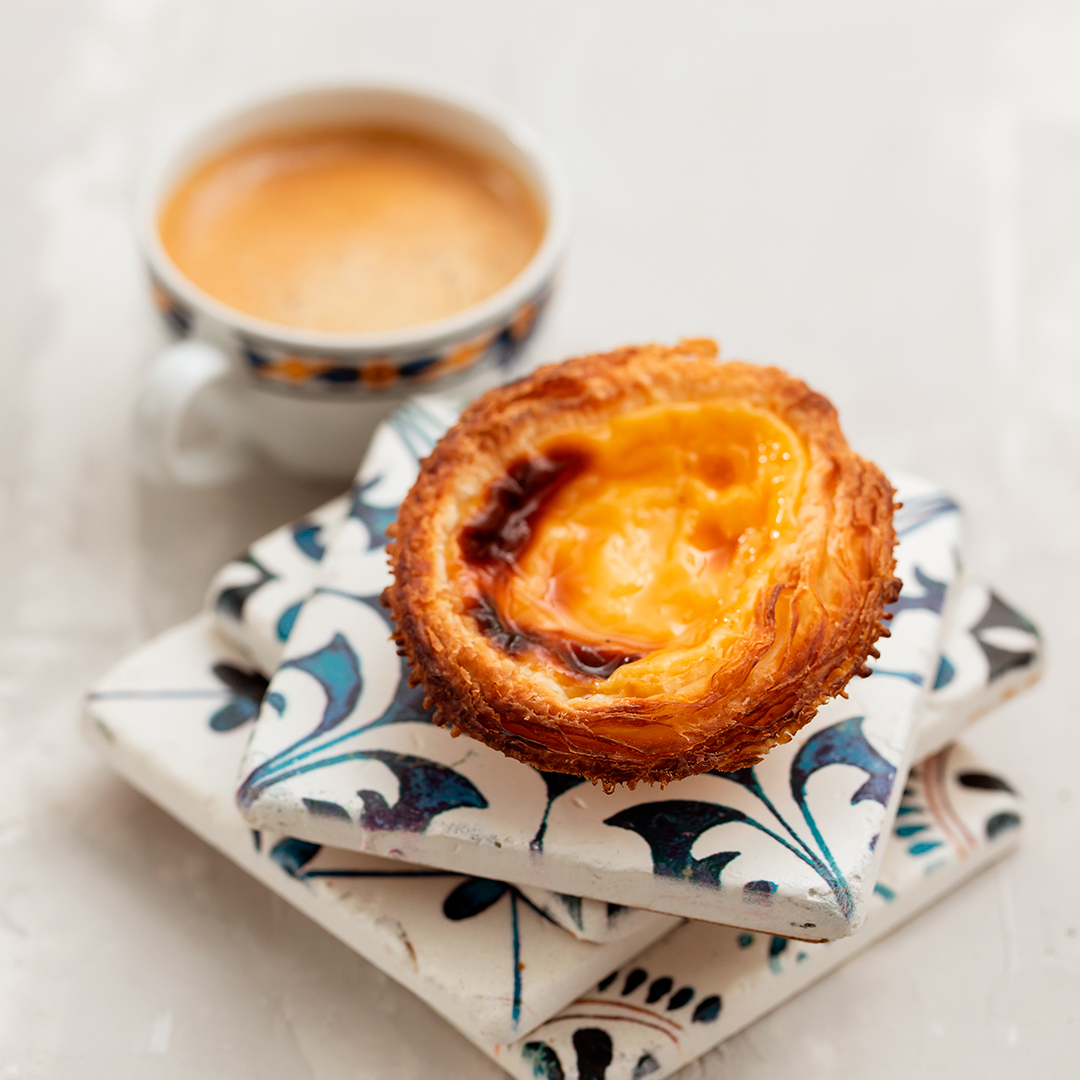 a cup of coffee and a pastry on a stack of tiles