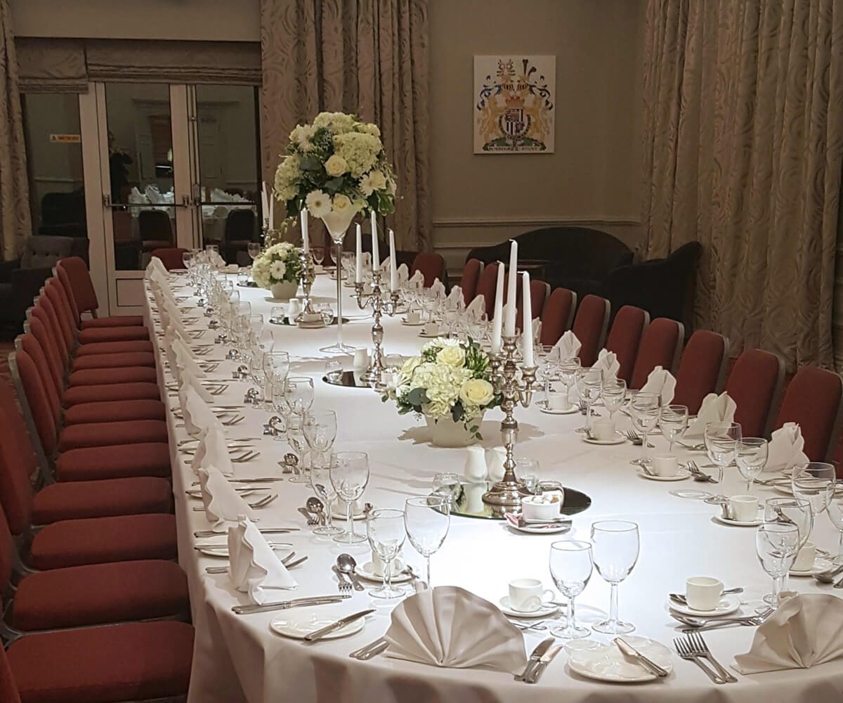 a long table with white tablecloths and white flowers