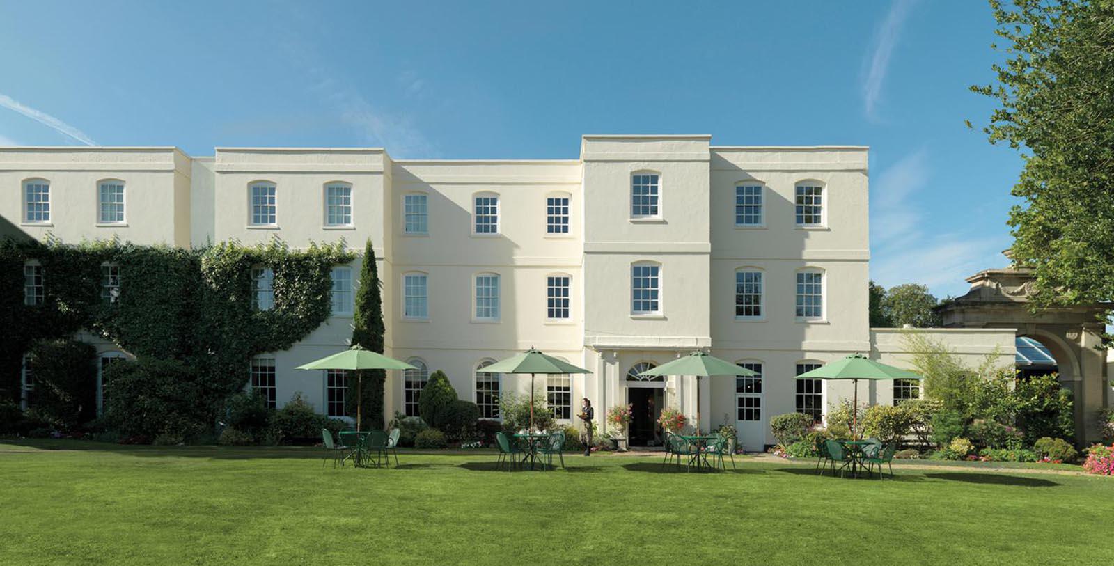 a white building with green lawn and chairs