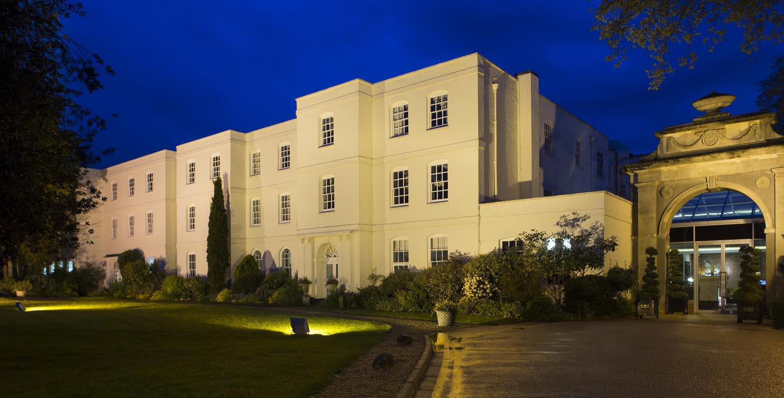 a large white building with a lawn and trees