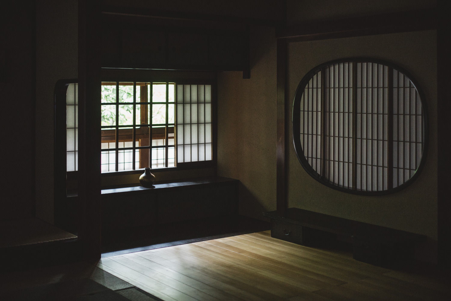 a room with a round window and a vase