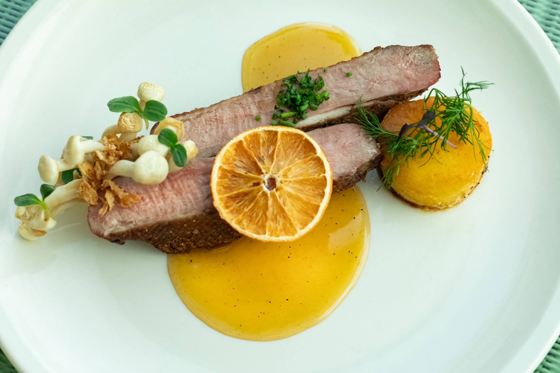 a plate of food with a slice of meat and orange slices