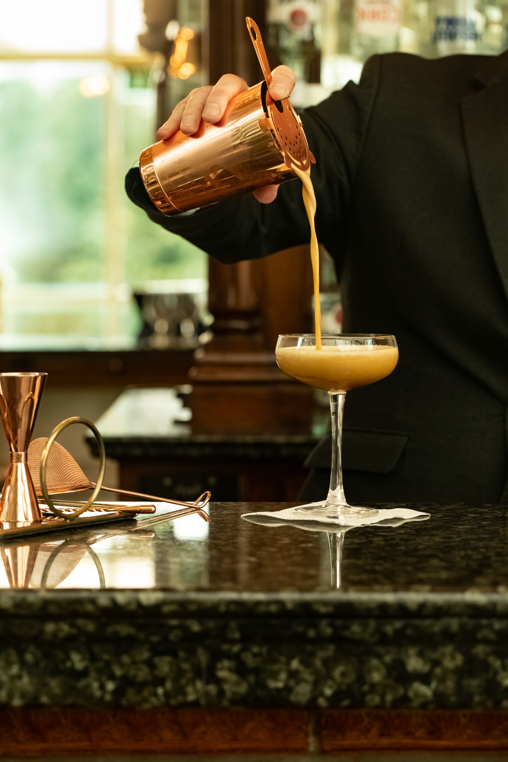 a person pouring a drink into a glass