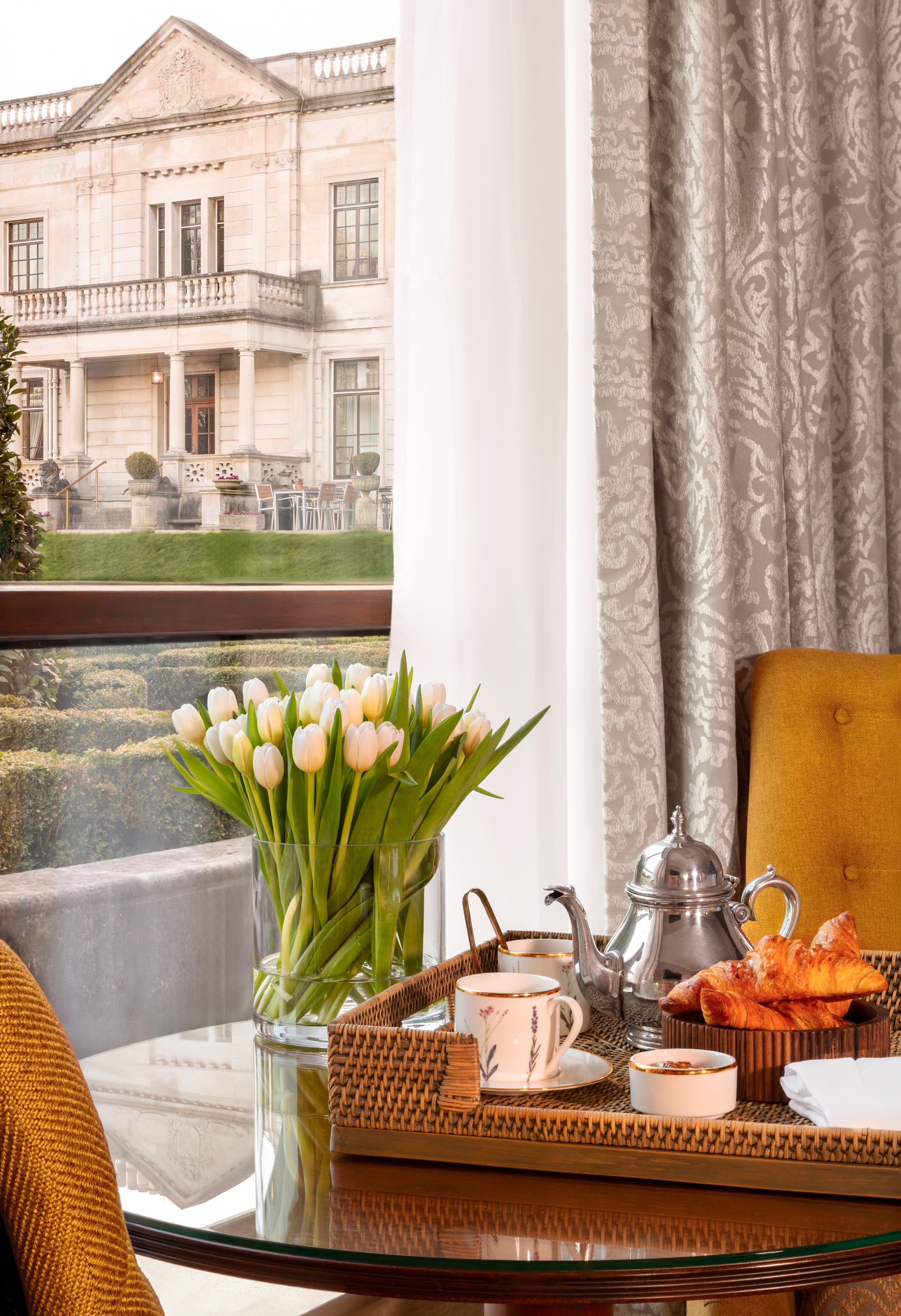 a table with a cup of tea and croissants and a vase of flowers