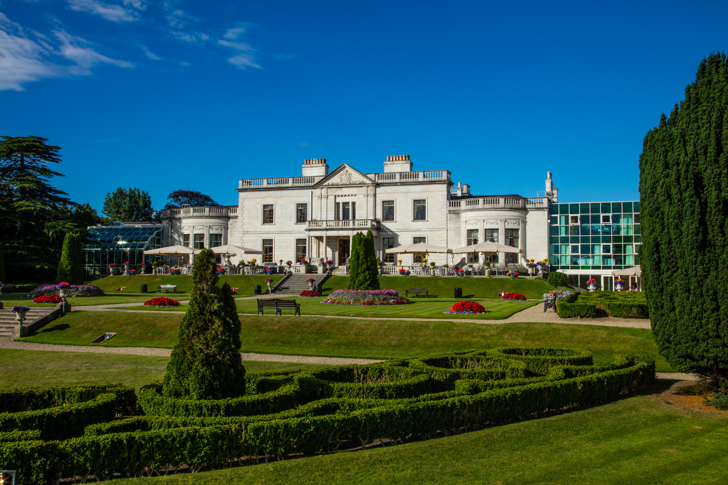 a large white building with a garden and bushes