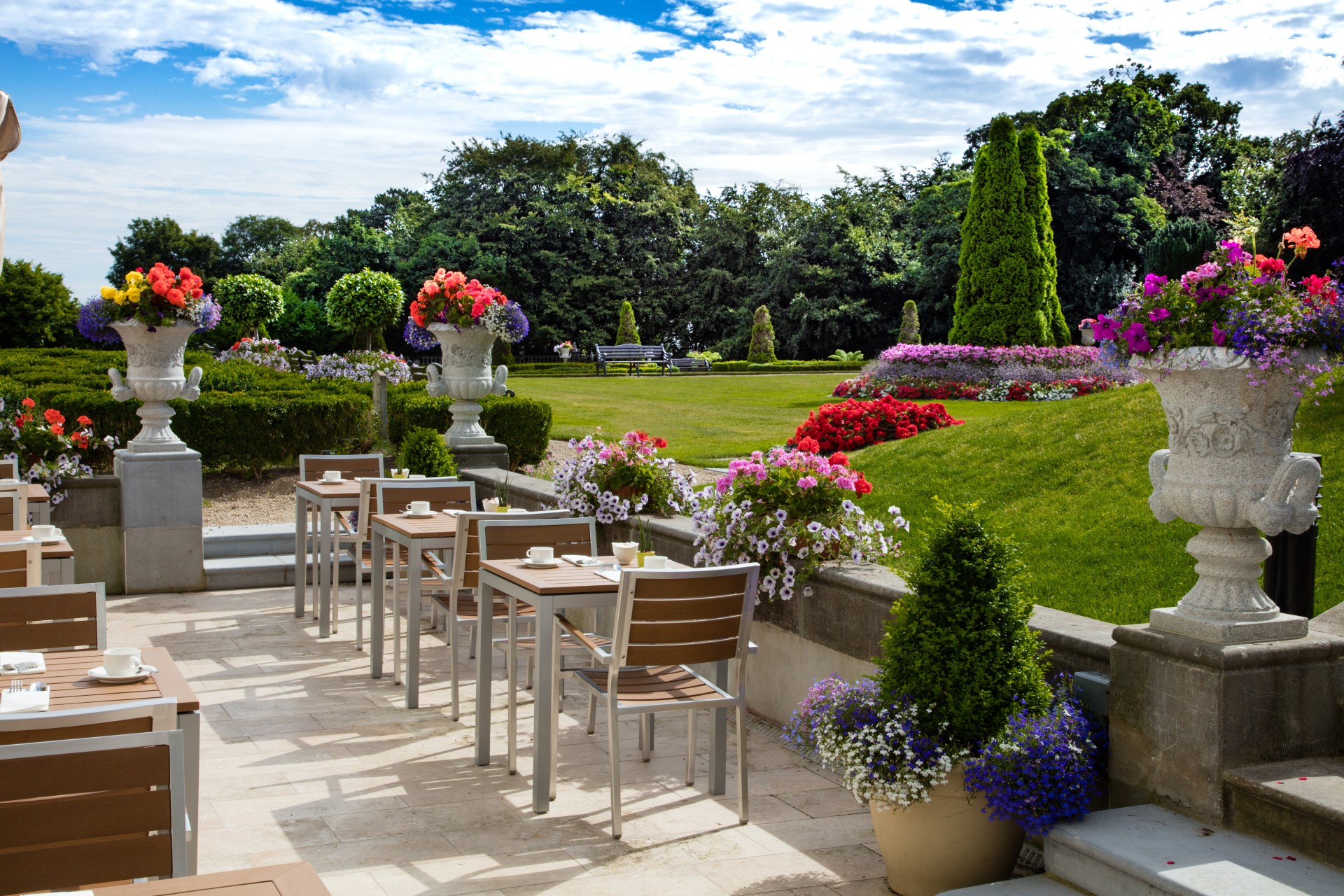 a table and chairs on a patio with flowers and trees in the background