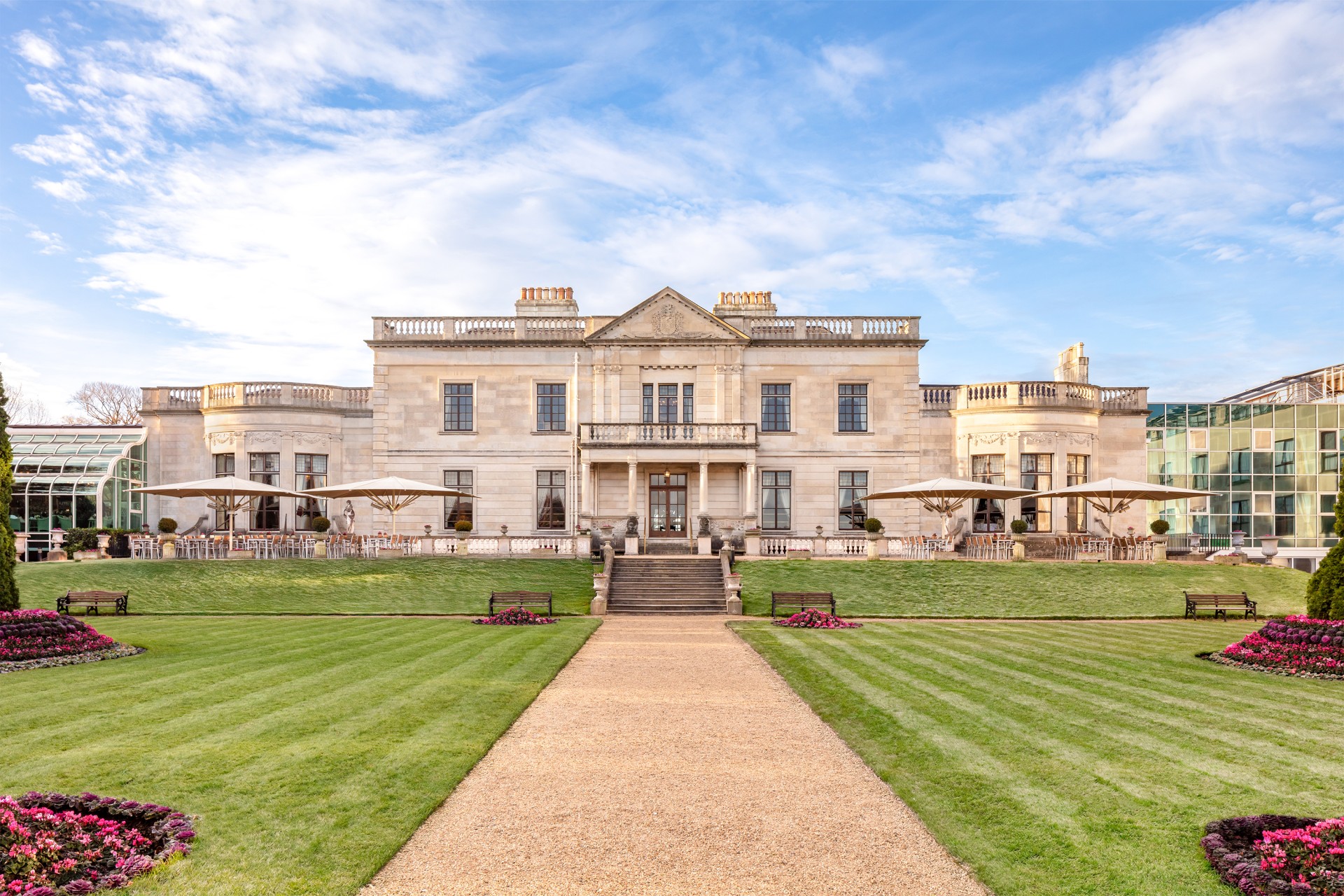 a large white building with a lawn and umbrellas with Brodsworth Hall in the background