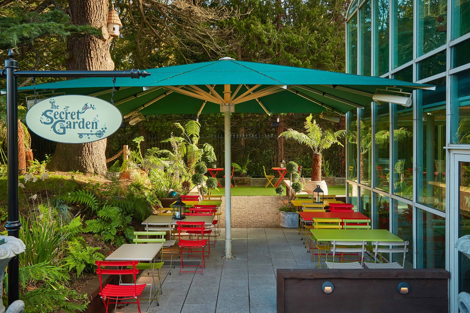 a patio with tables and chairs under a green umbrella