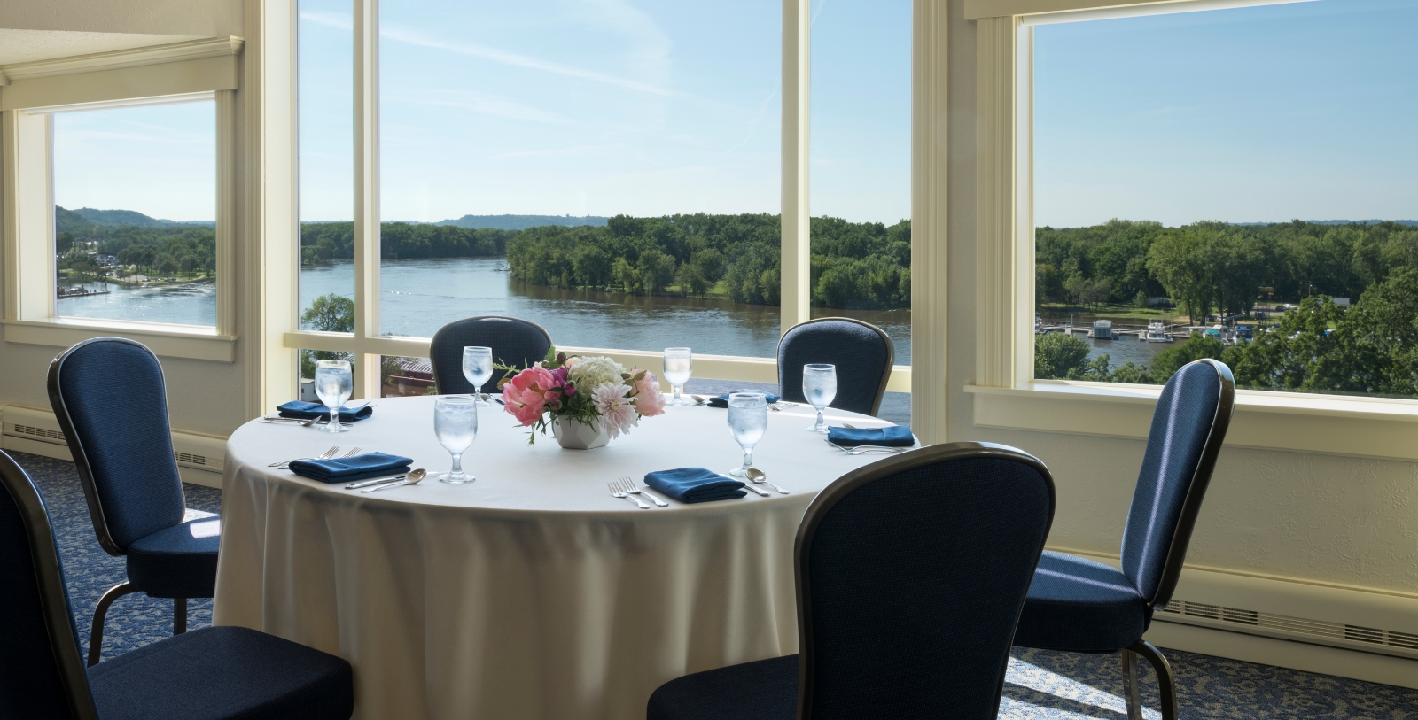 a table set for a dinner with a view of water and trees