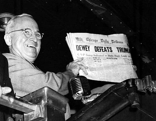 a man smiling while holding a newspaper