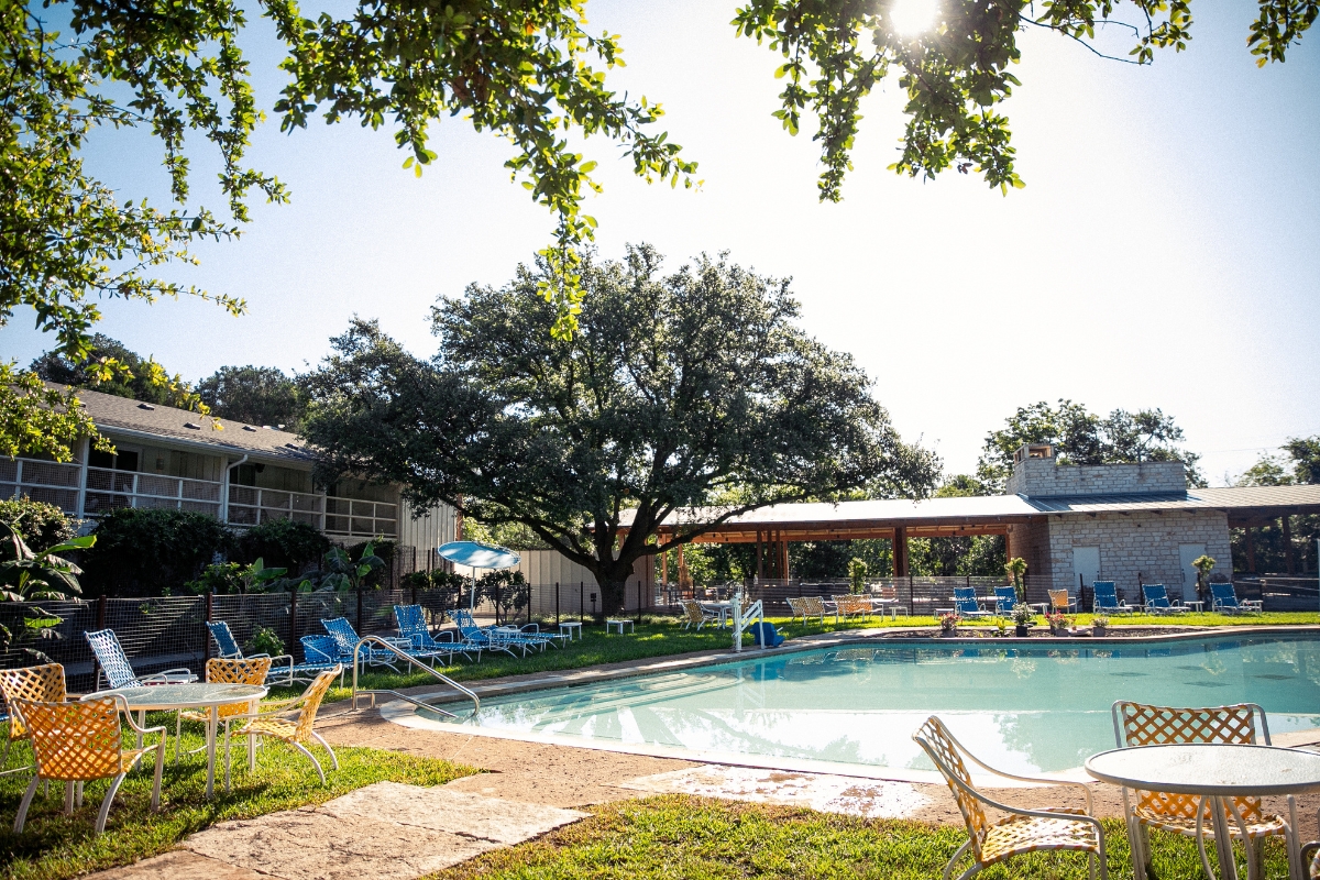 a pool with chairs and a building in the background