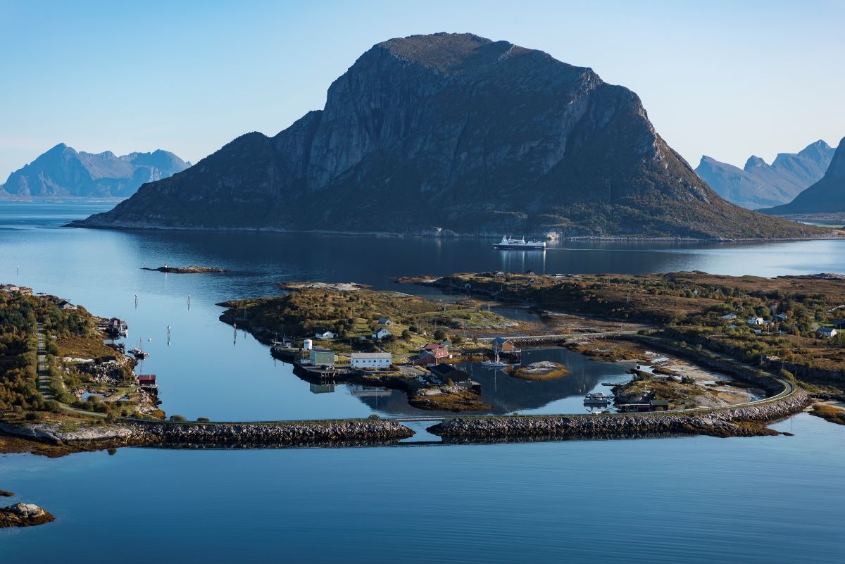 a small island in the water with Lofoten in the background