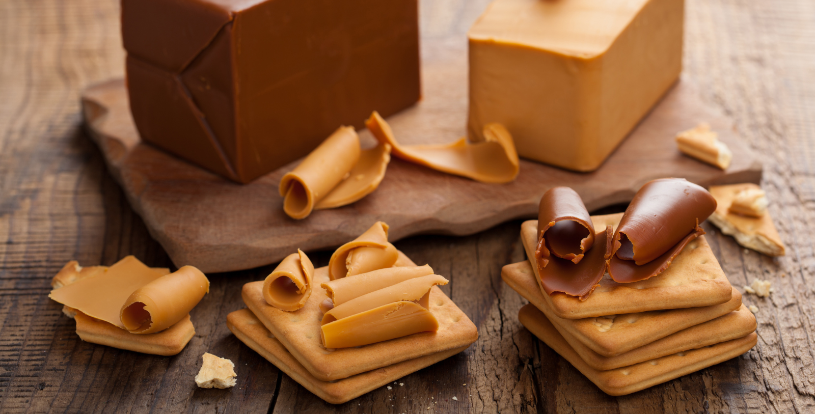 crack crackers with cheese and chocolate curls on a wooden surface